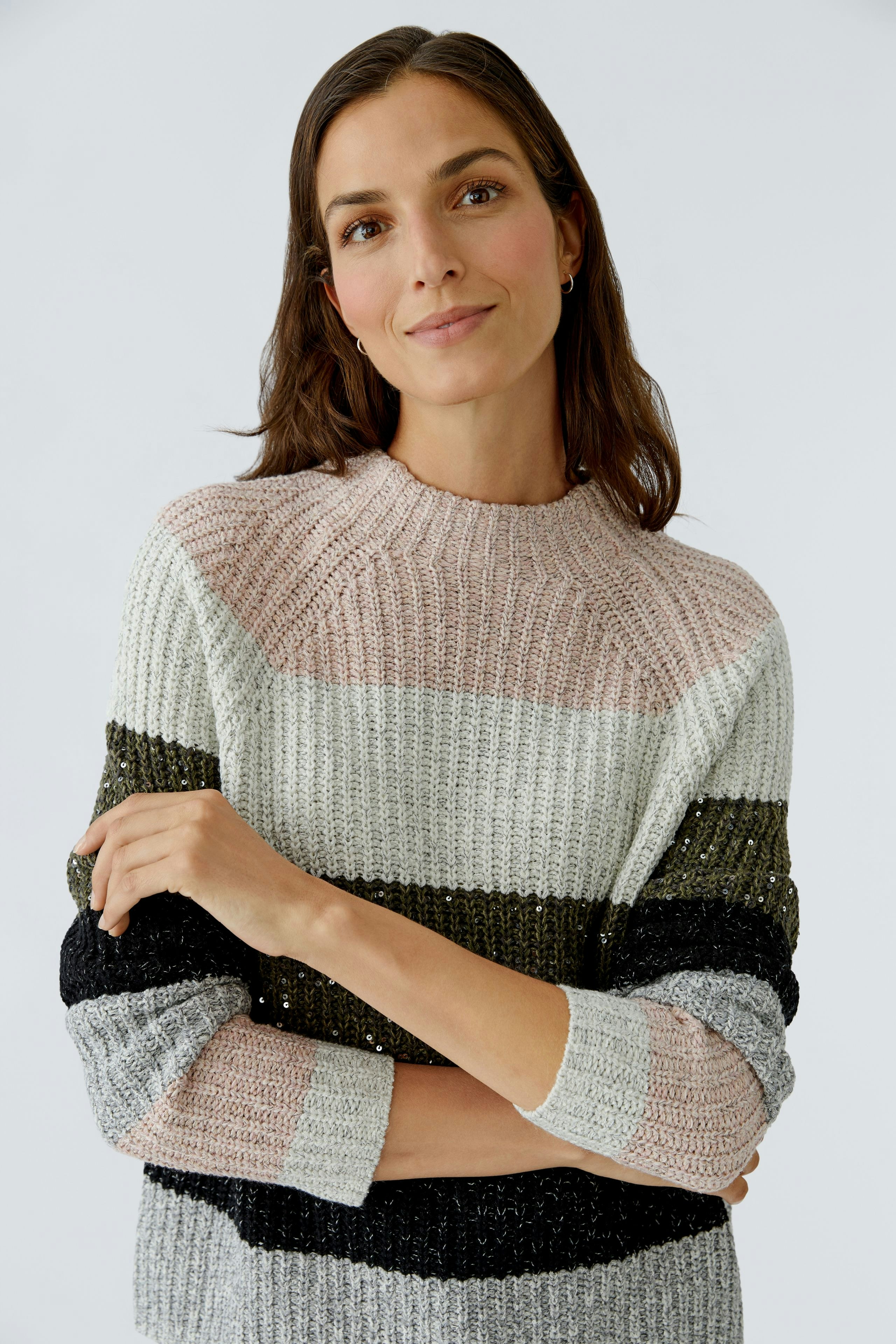 Casual women's pullover: Young woman in a striped knit pullover with soft colors, smiling confidently.