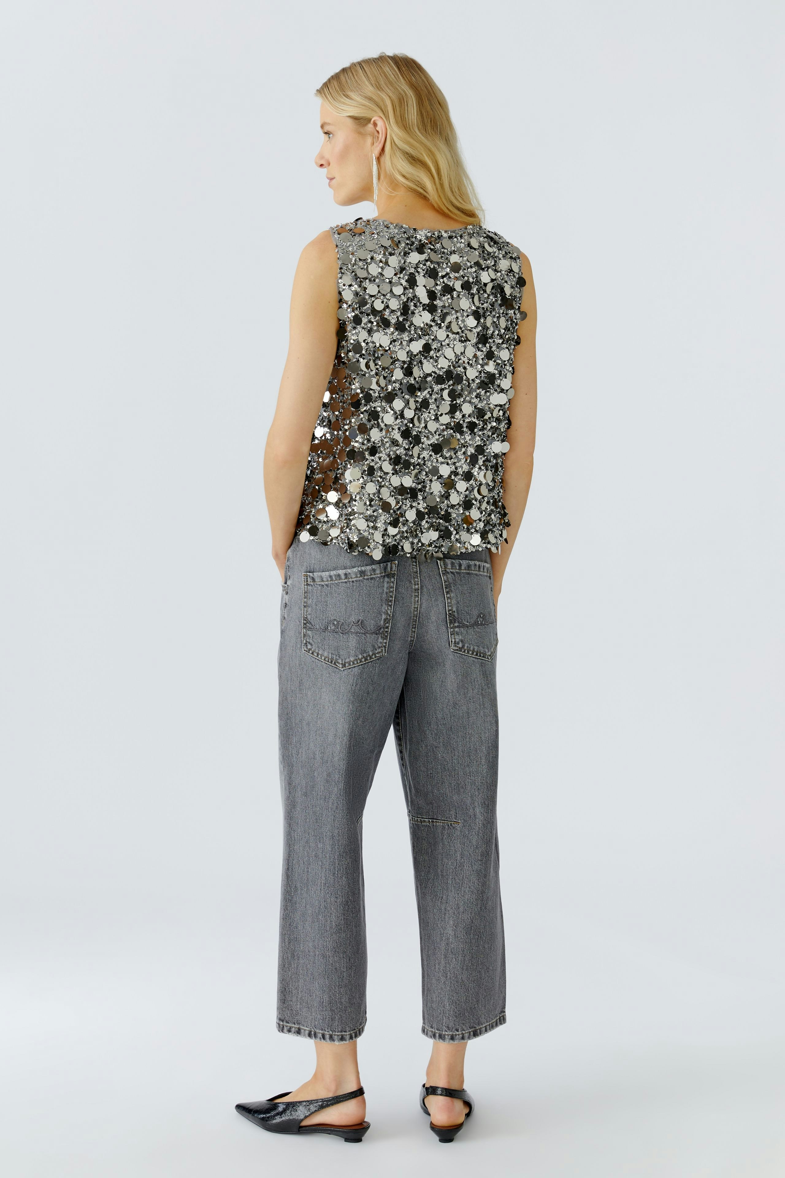 Stylish women's top: A woman in a sequined sleeveless top paired with relaxed-fit jeans.