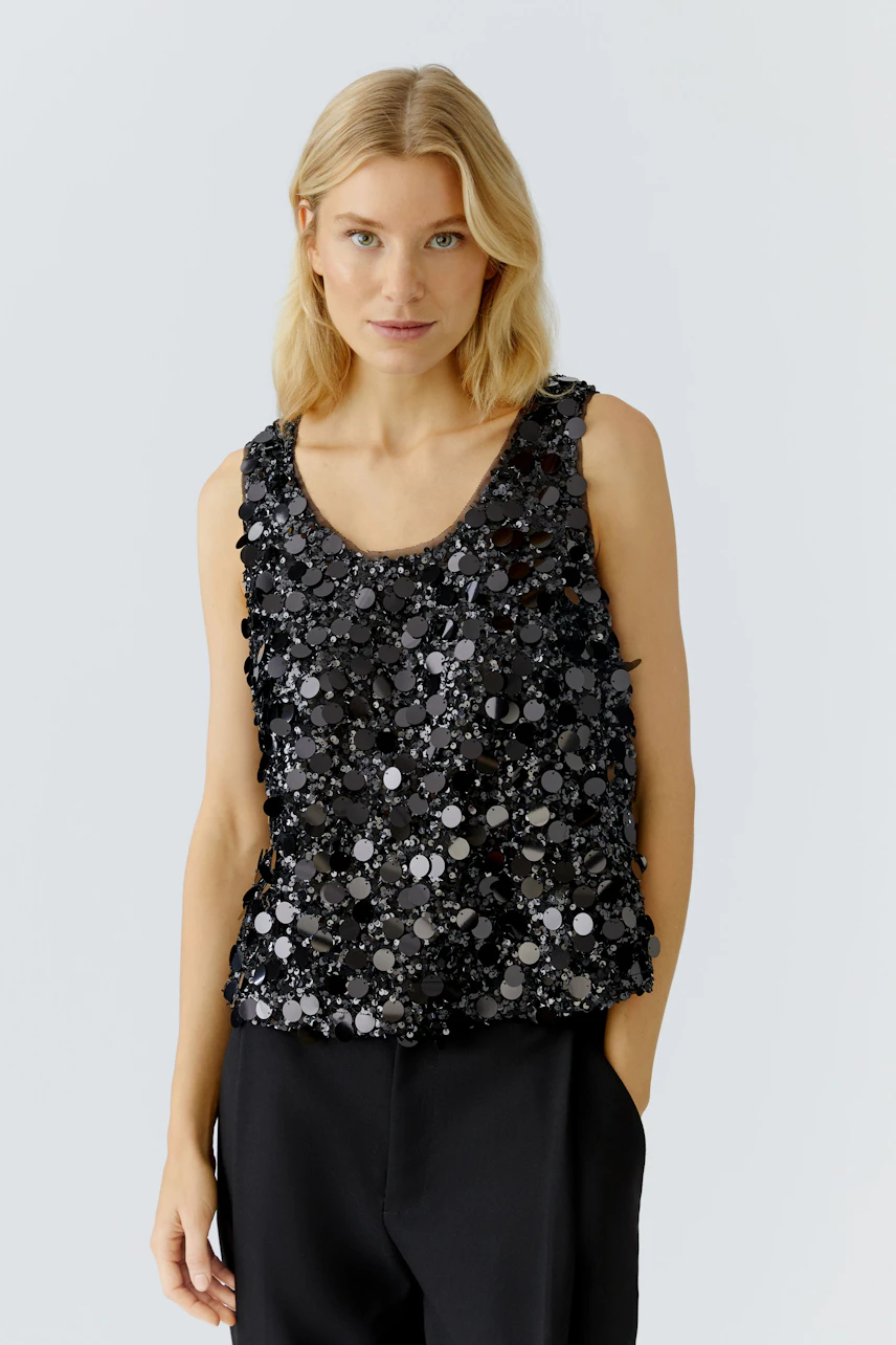 Schwarzes Damen-Top mit glitzernden Pailletten, lässig kombiniert mit einer schwarzen Hose.