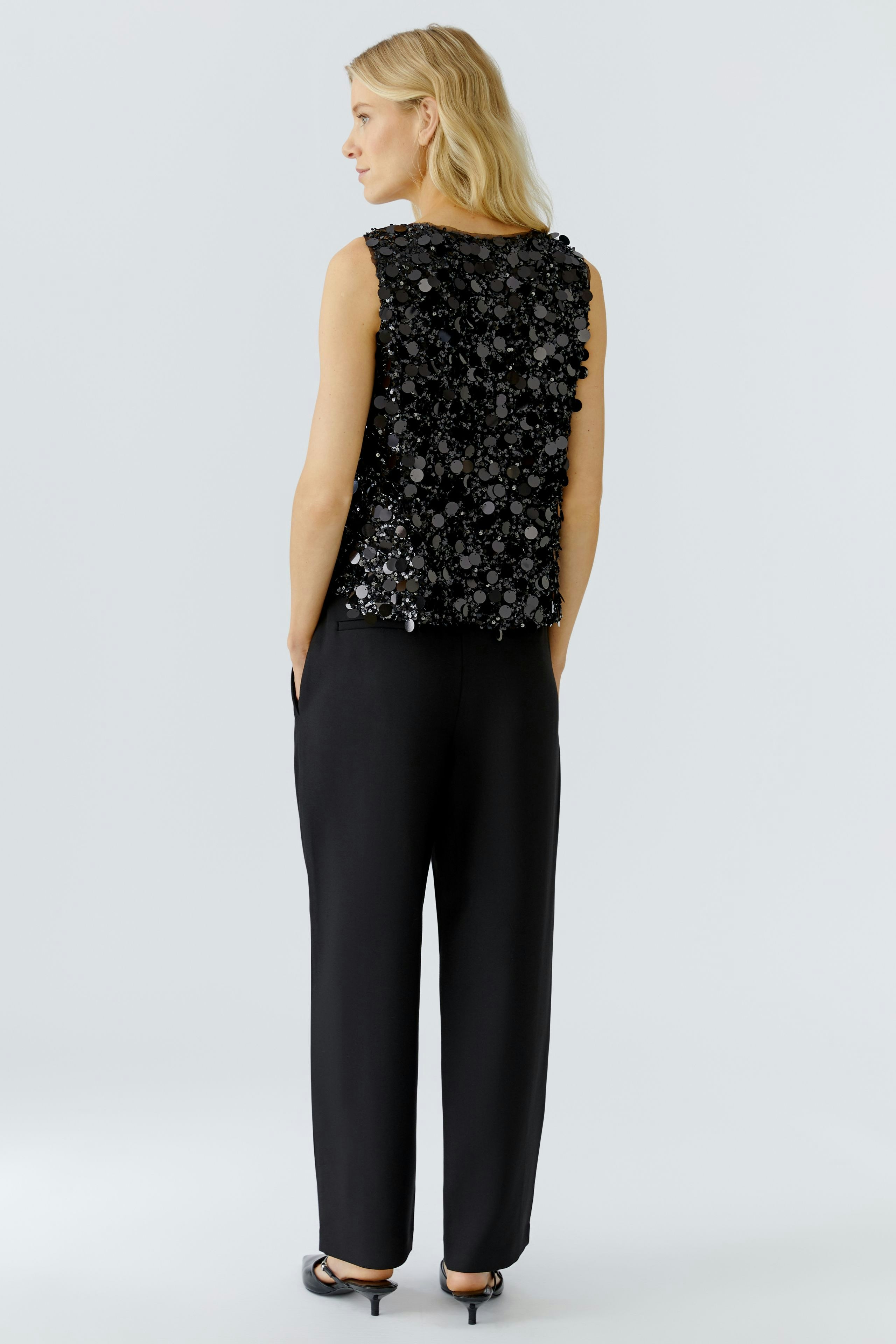 Stylish women's top: A woman in a black sequined sleeveless top, showcasing a modern design.