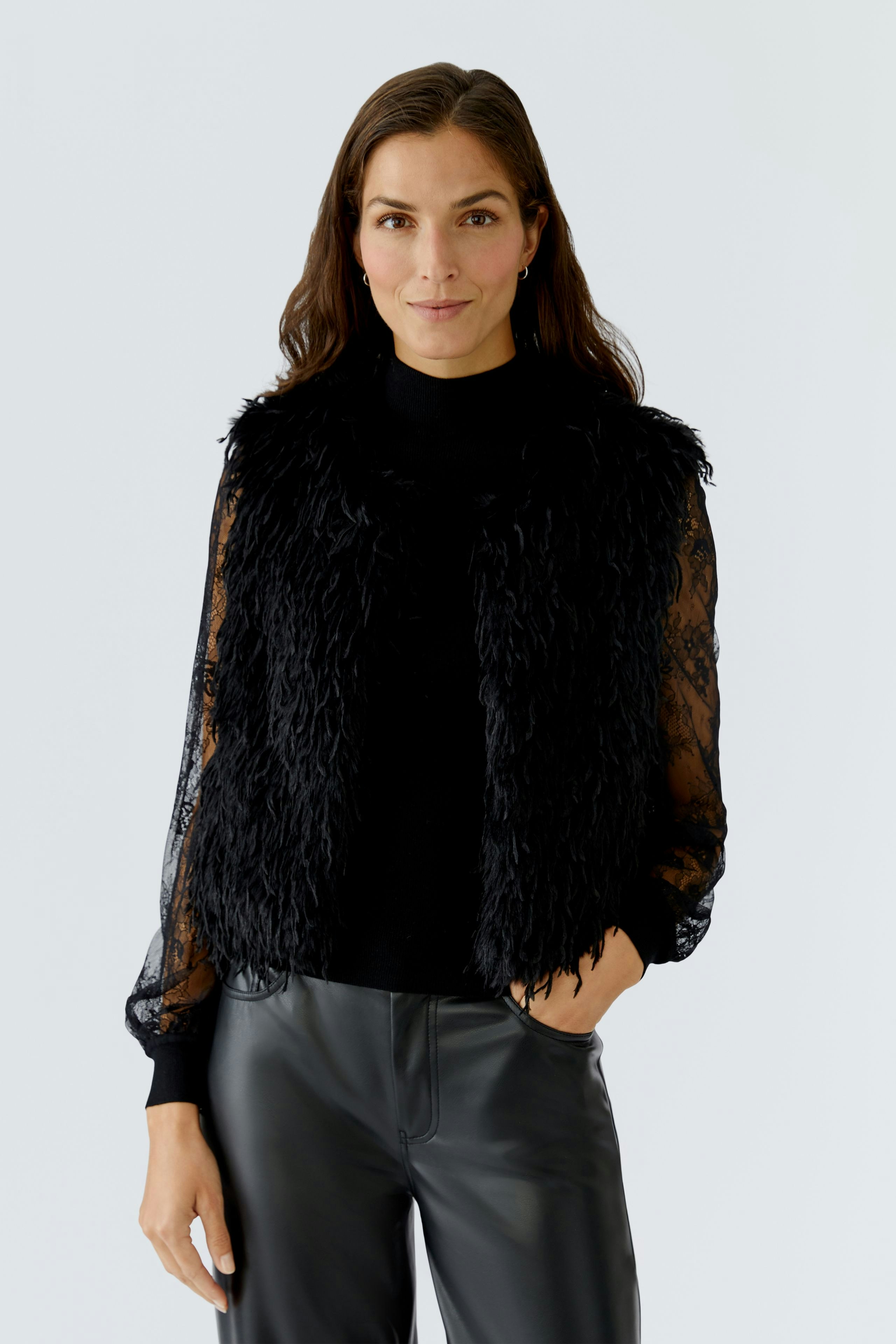 Stylish women's vest: A woman in a black fluffy vest over a long-sleeve top, paired with sleek pants.