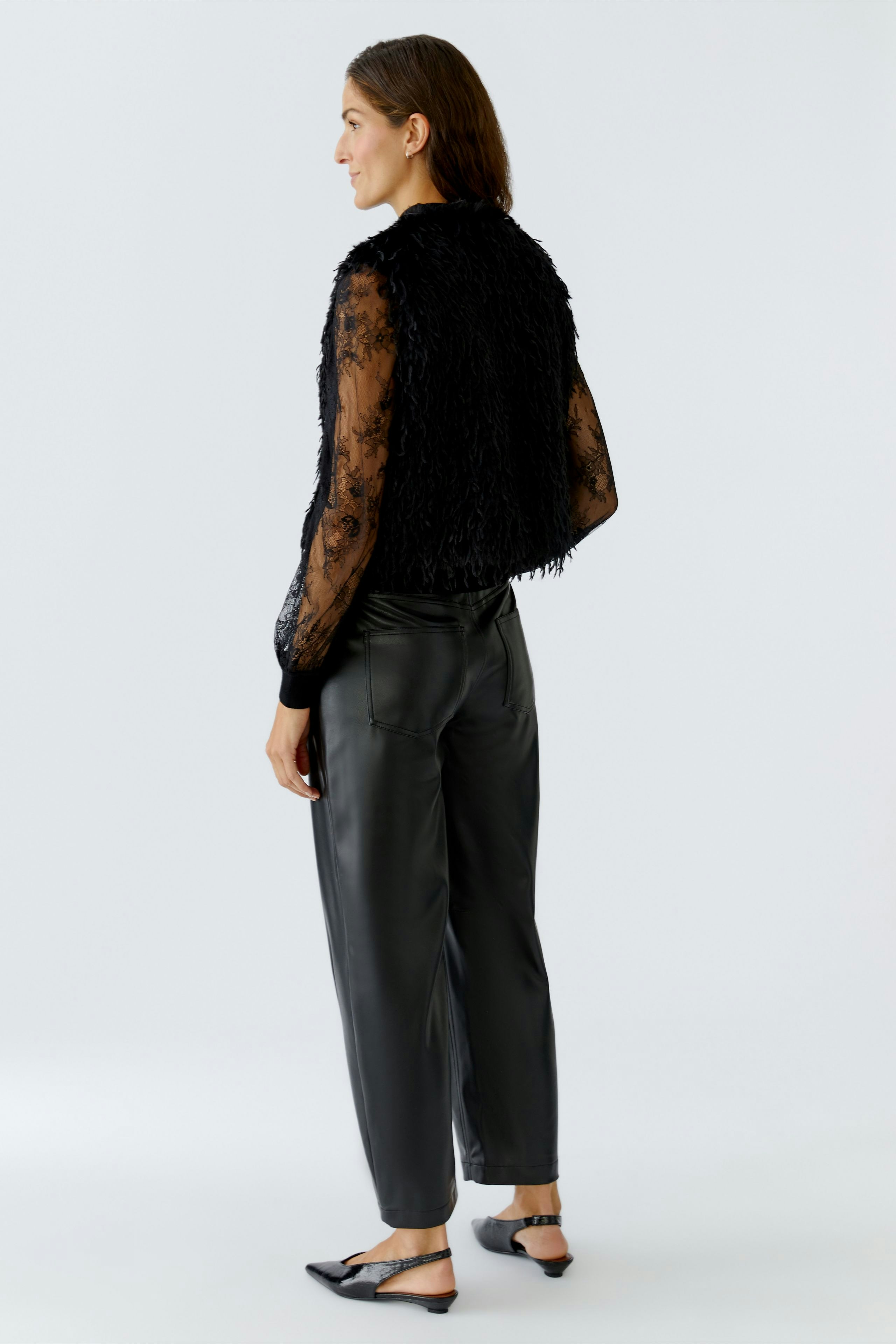 Casual women's vest: A woman in a black fringed vest paired with sleek pants, showcasing a relaxed style.