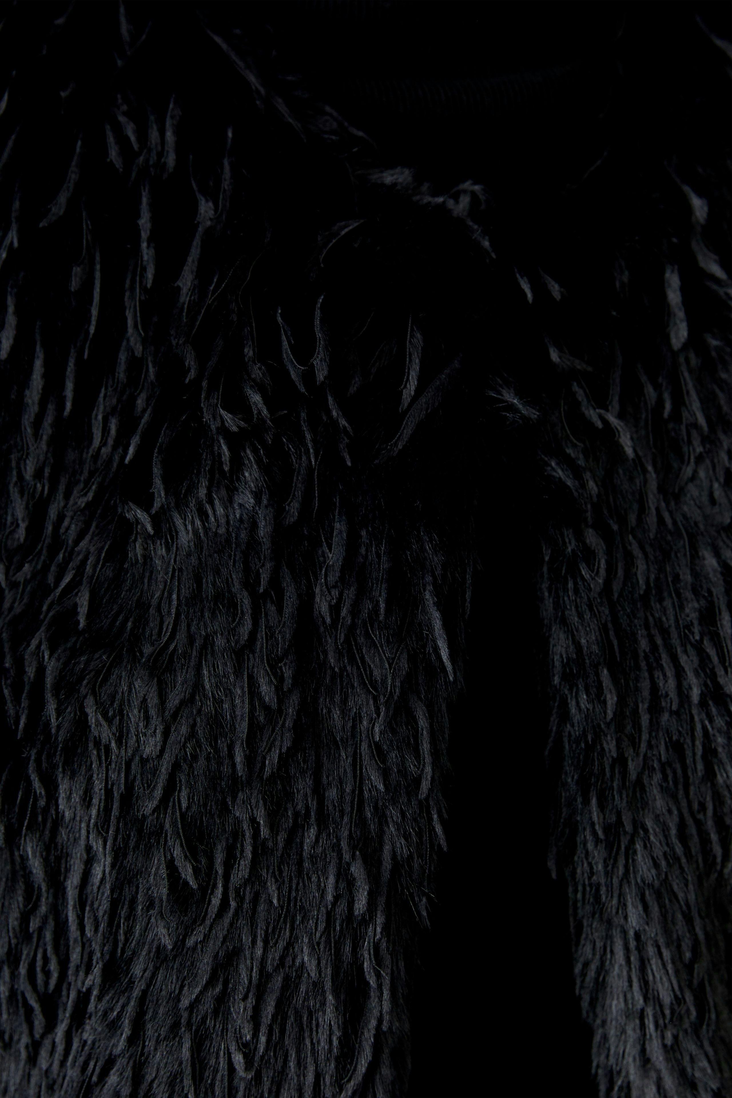 Faux fur vest: Close-up of a woman's black vest with a soft, textured finish.