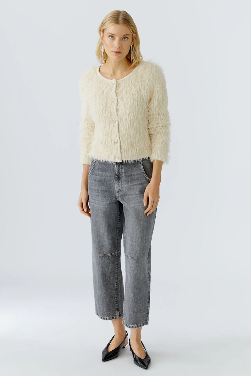 Casual women's jeans barrel: Young woman in gray jeans with a fluffy cream cardigan, standing confidently.