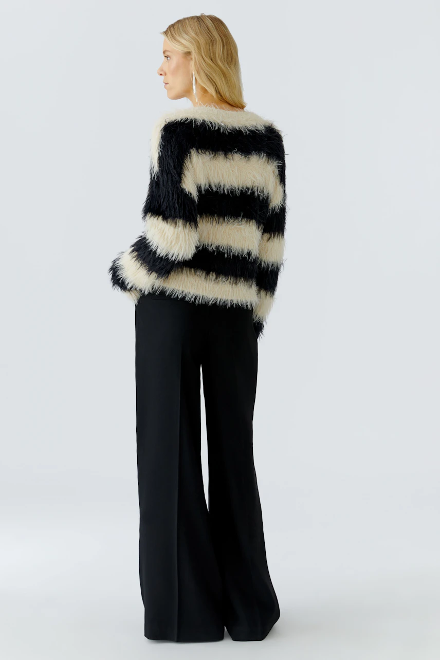 Casual women's pullover: A woman in a striped, fluffy pullover with black and cream colors.