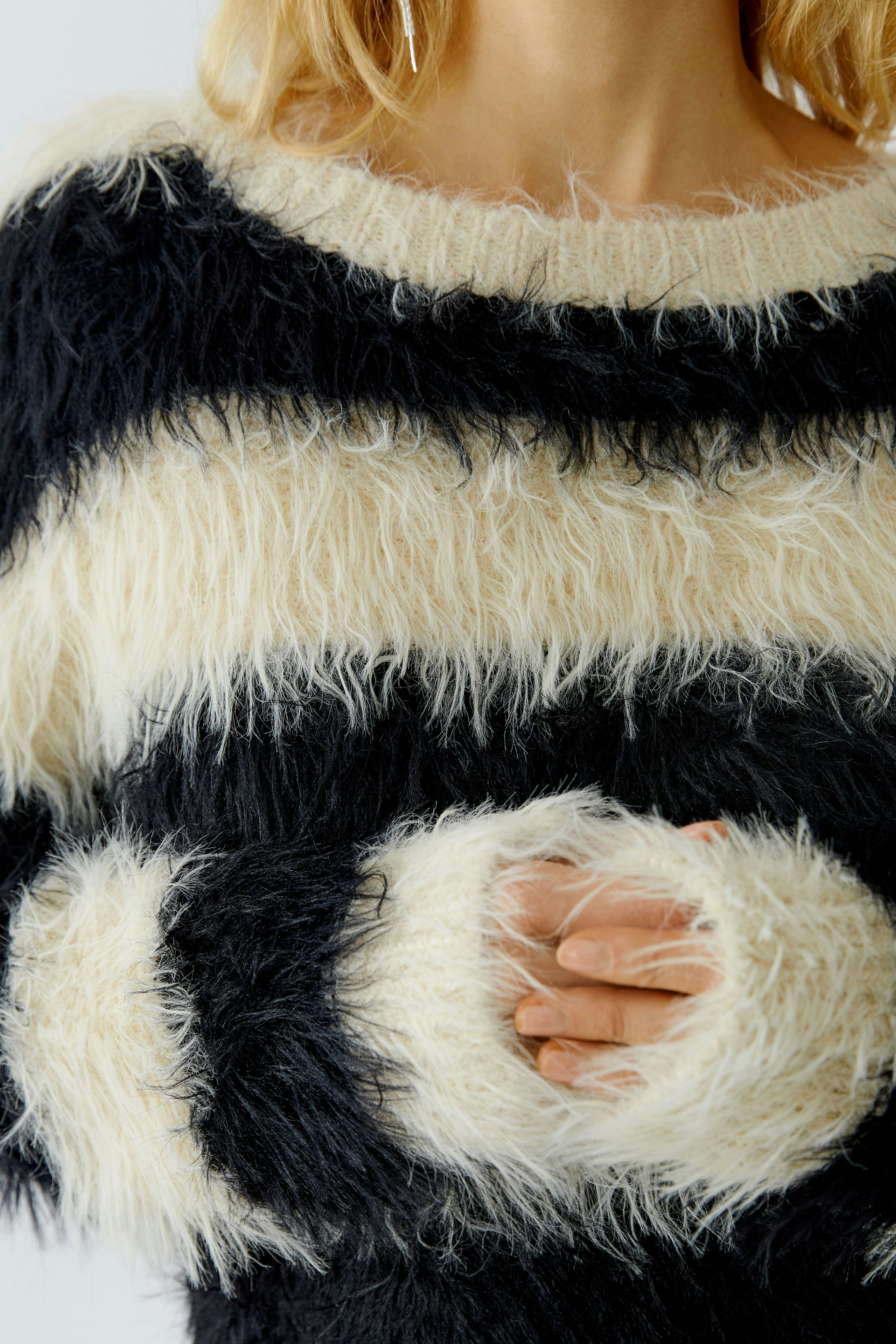 Cozy women's pullover: A woman in a fluffy black and cream striped pullover with soft sleeves.