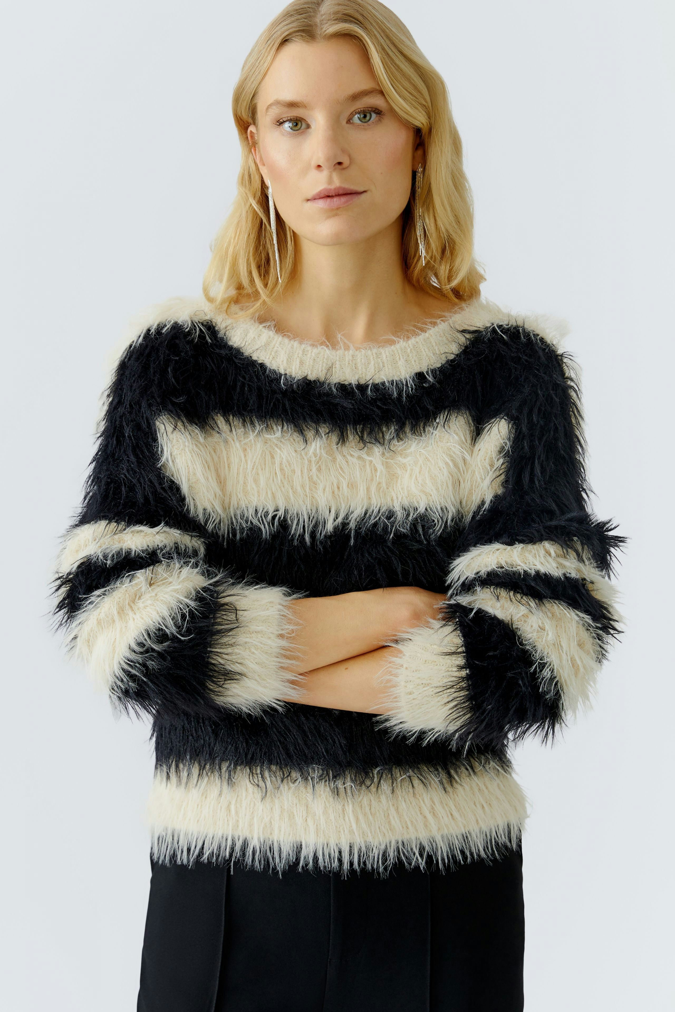 Casual women's pullover: A woman in a fluffy striped pullover with black and cream colors, arms crossed.