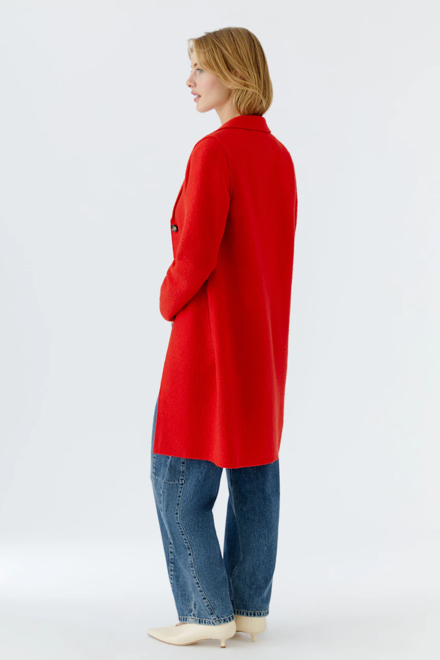 Stylish women's wool coat in vibrant red, paired with relaxed jeans and chic shoes.