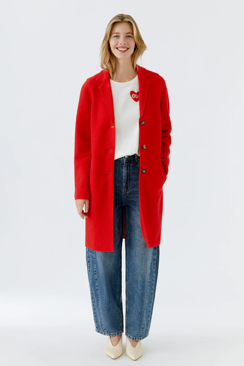 Stylish women's wool coat in vibrant red, paired with a white top and relaxed jeans.