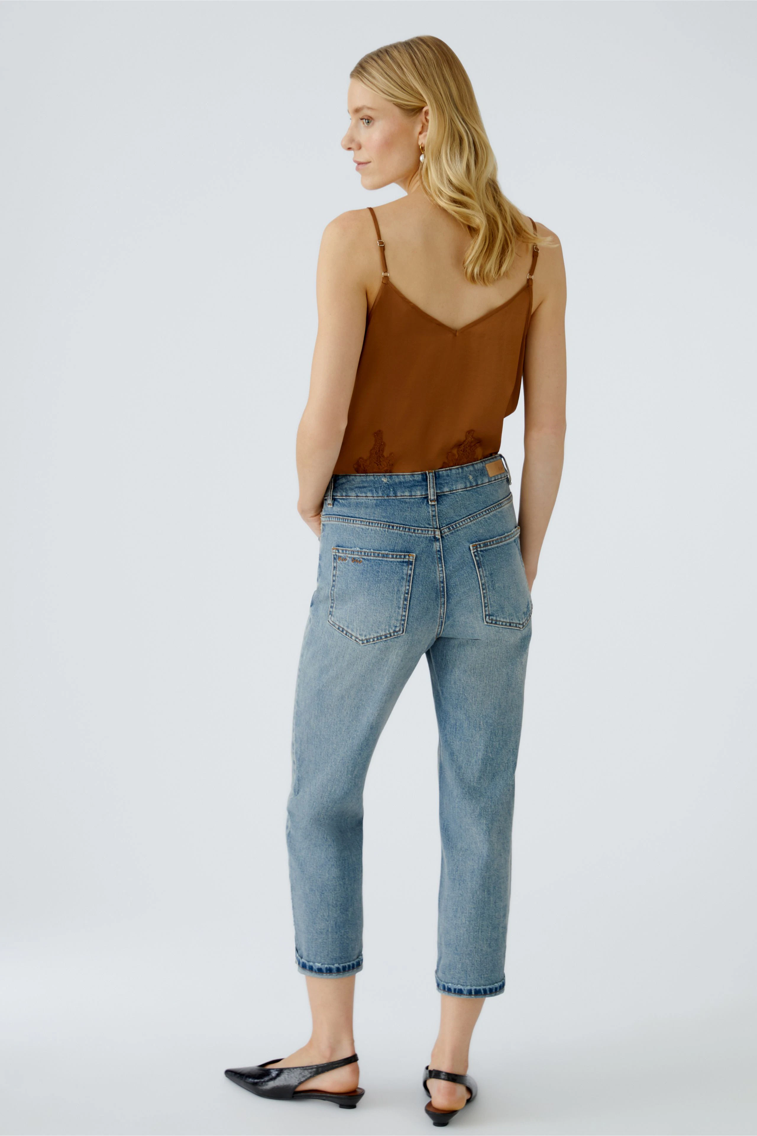 Casual women's outfit: Young woman in a brown top and light blue jeans, showcasing a relaxed style.