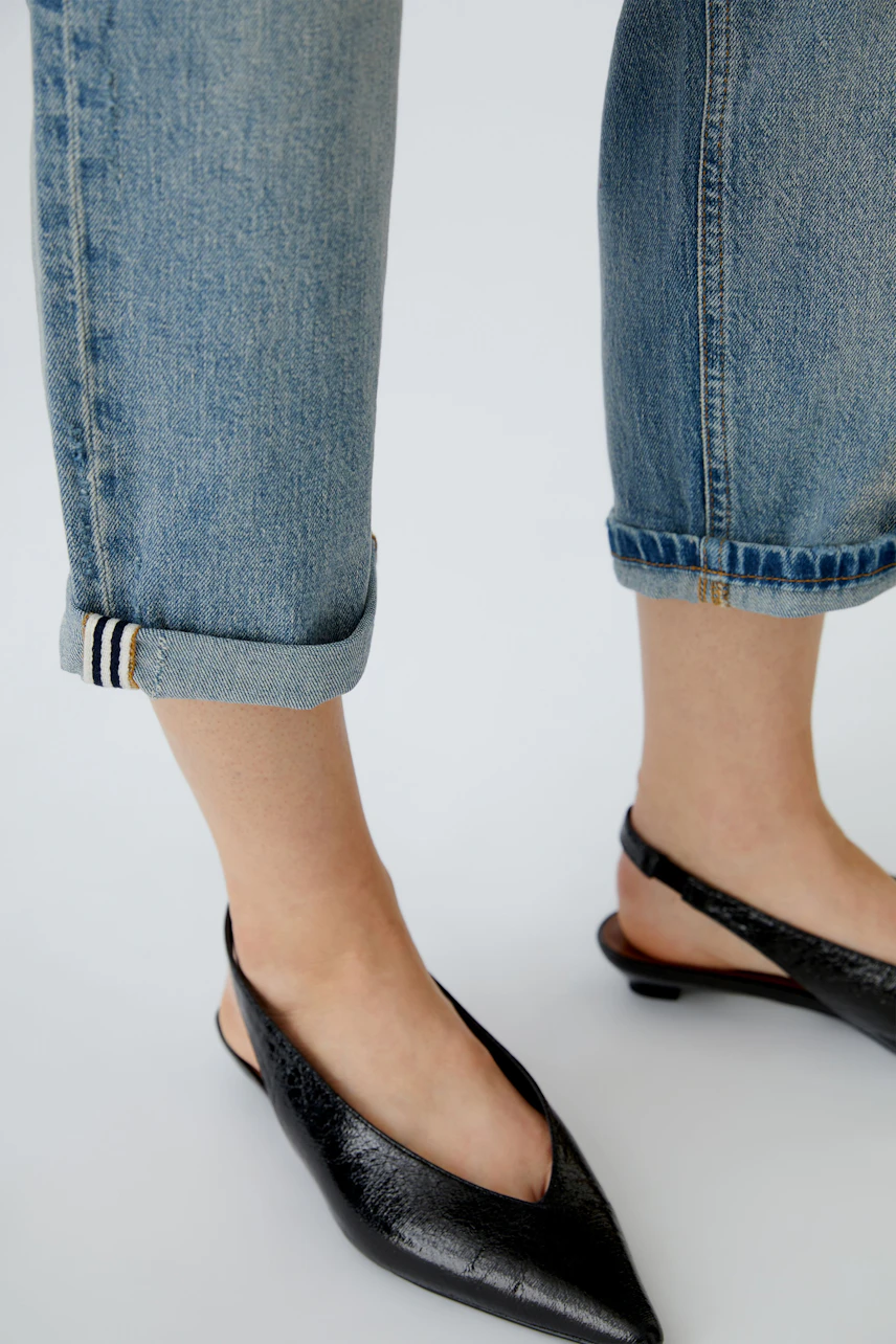 Casual women's outfit: Close-up of rolled-up jeans and stylish black slingback shoes.