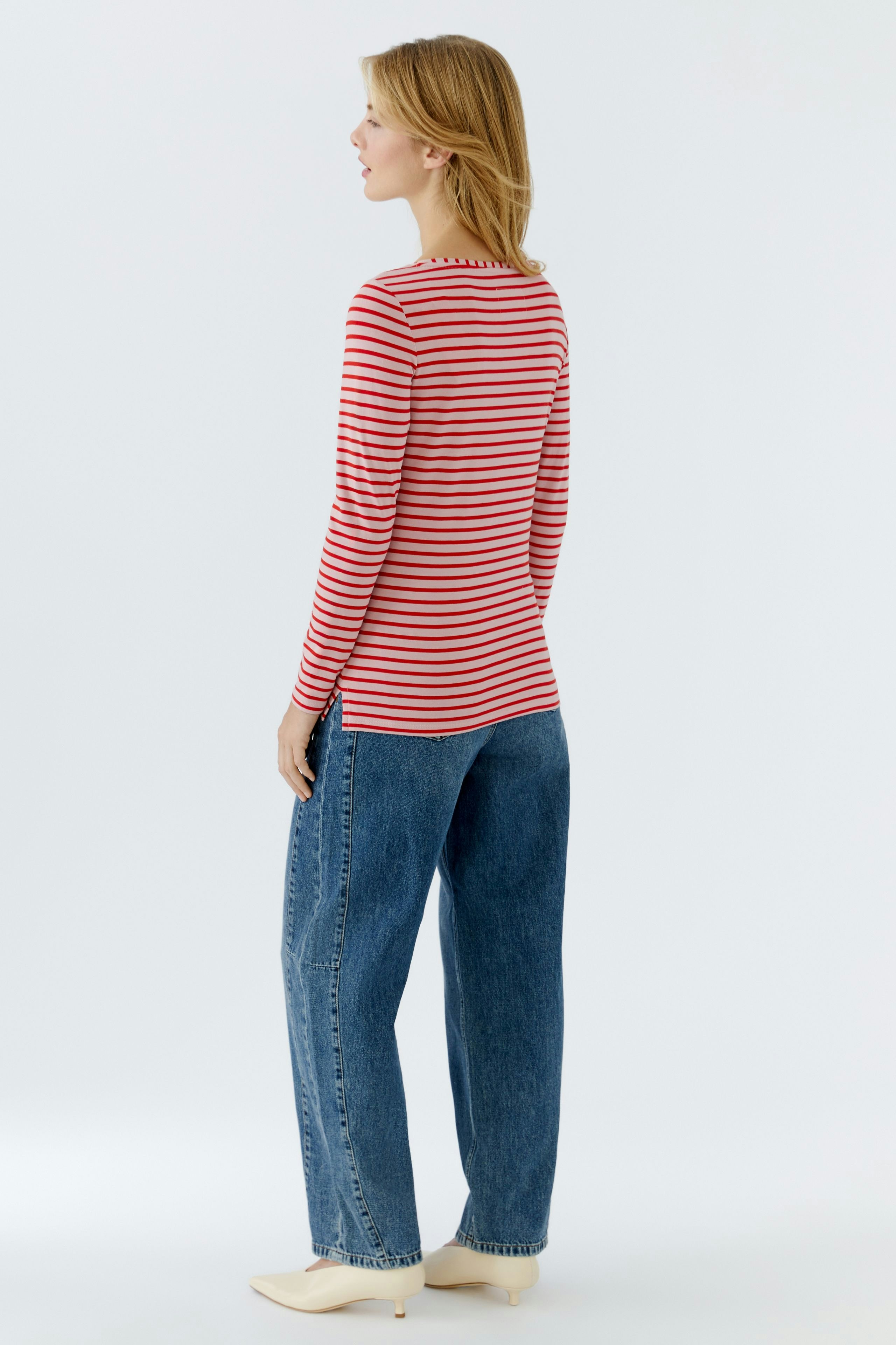 Casual long-sleeve shirt: Woman in a red and white striped shirt paired with relaxed-fit jeans.