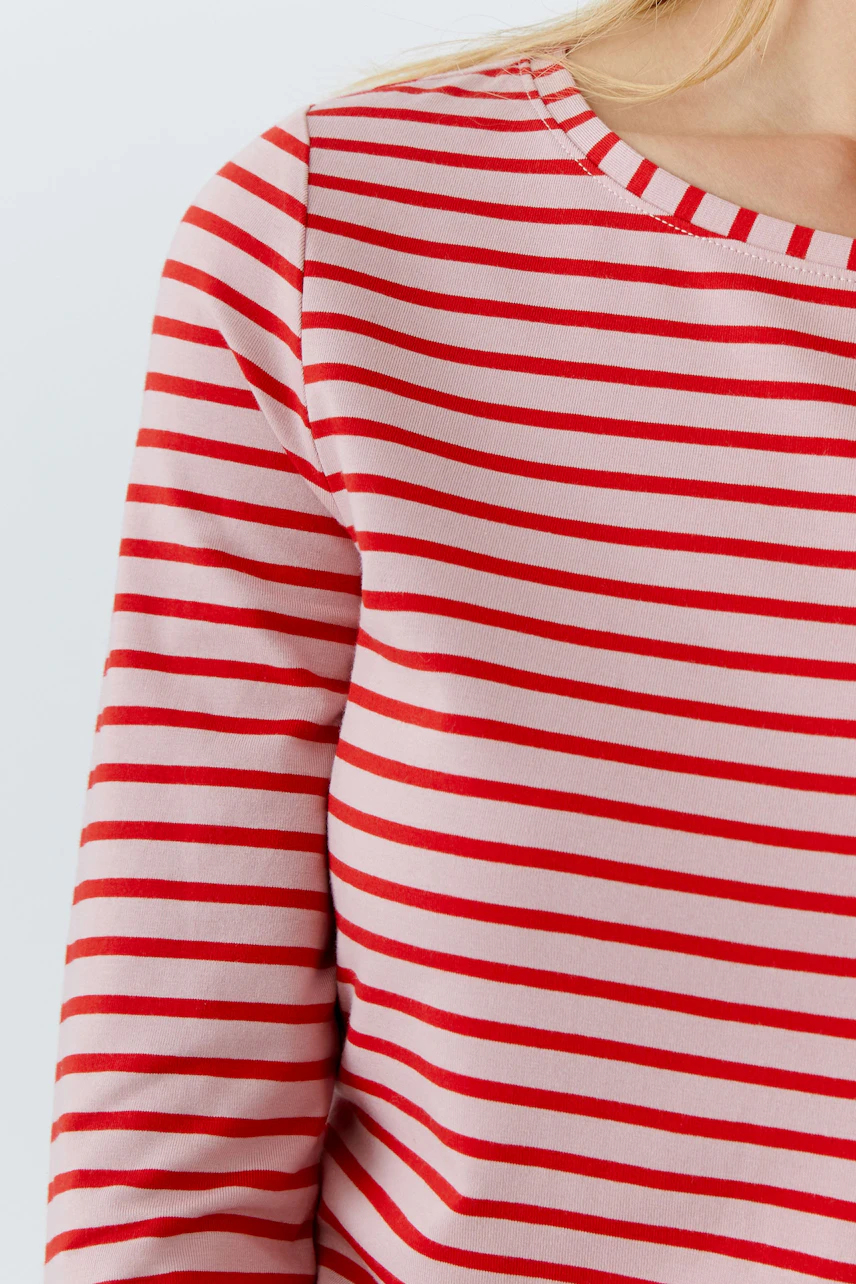 Casual long-sleeve shirt: Woman in a pink and red striped pullover, showcasing a relaxed style.