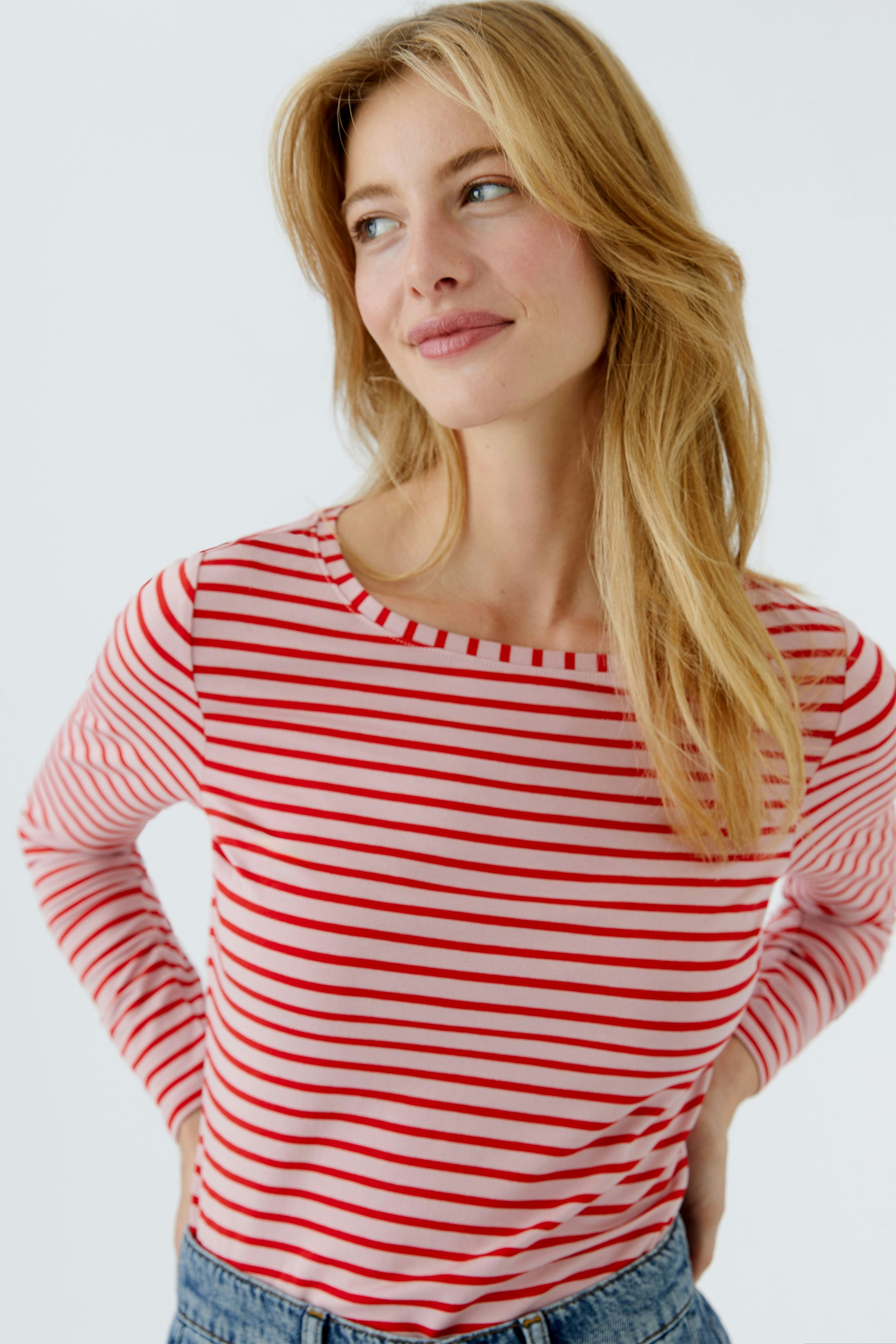 Casual long-sleeve shirt: Woman in a red and white striped shirt, smiling and looking relaxed.