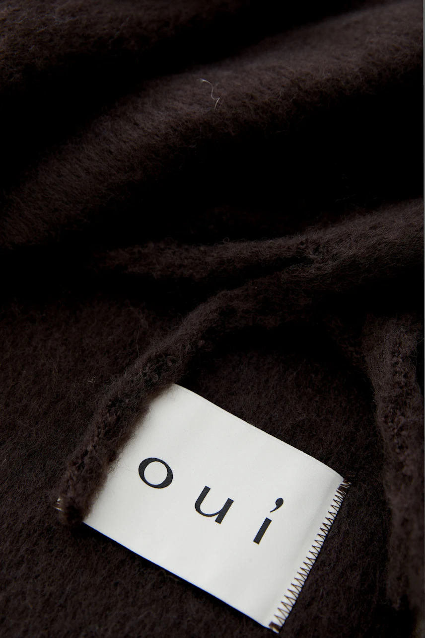 Cozy women's scarf in dark brown, styled with a matching coat and casual jeans.