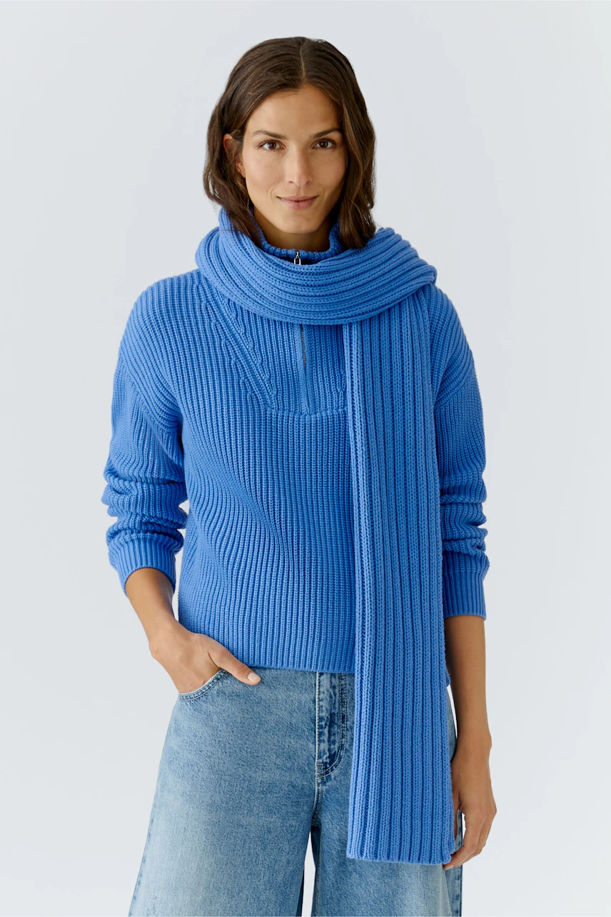 Cozy women's scarf paired with a blue pullover, styled with relaxed denim.