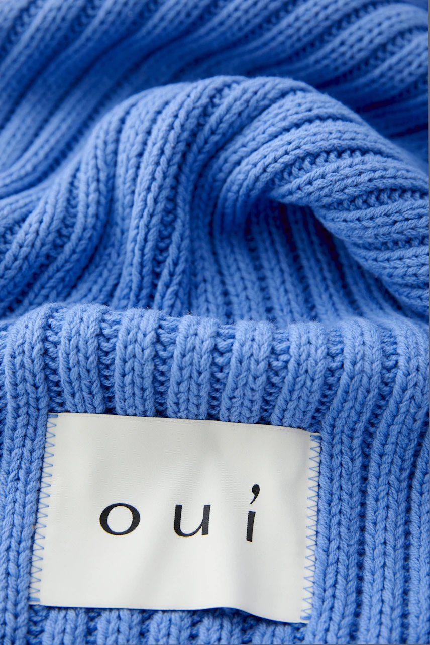 Soft blue scarf with a textured knit, showcasing the oui brand label.