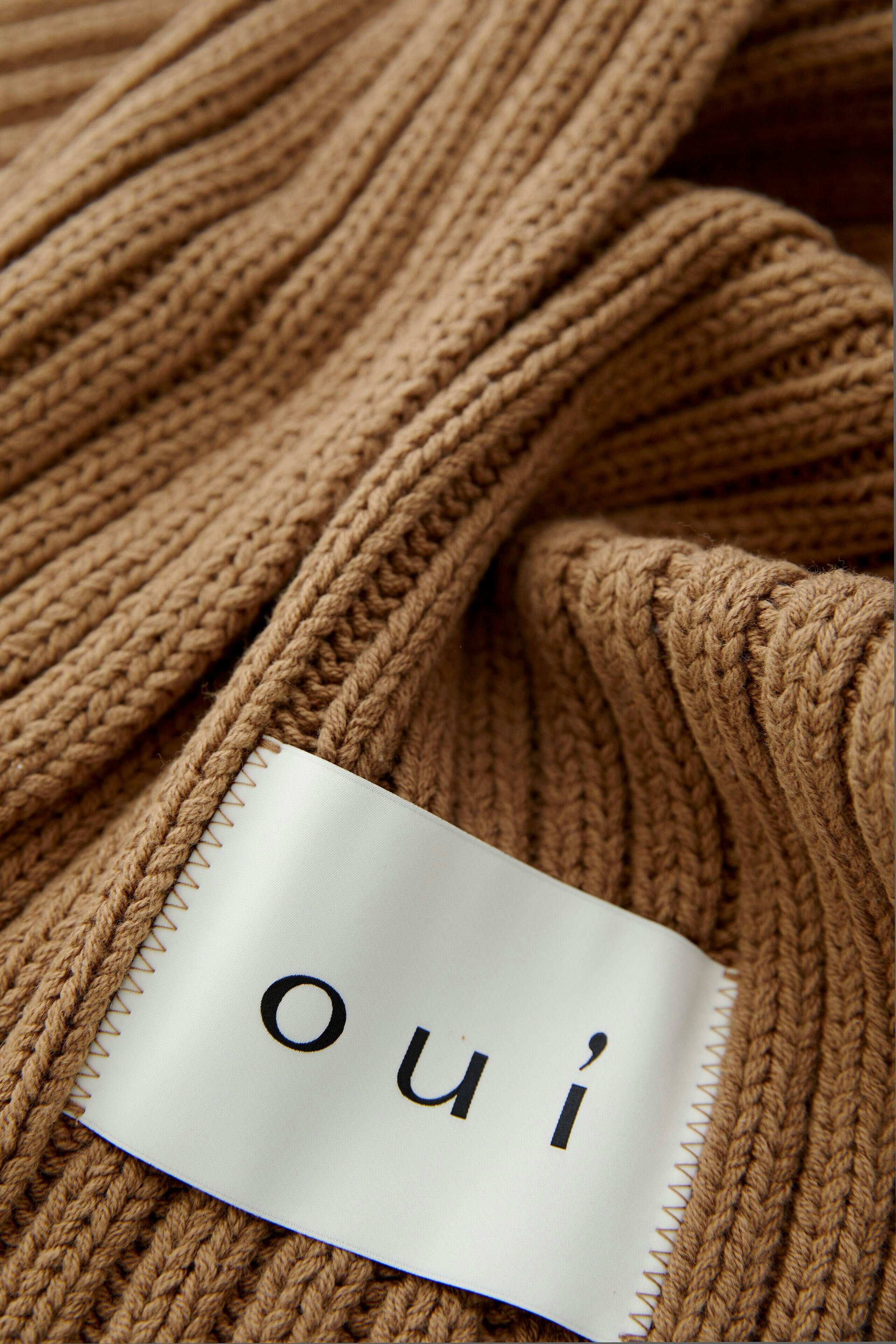 Cozy women's scarf in ribbed knit, featuring a logo patch, perfect for casual outfits.