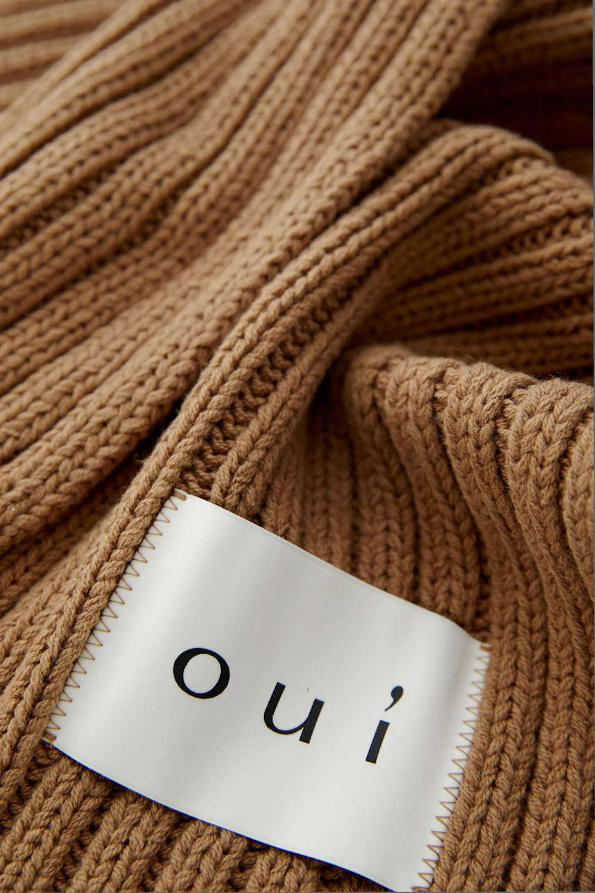 Cozy women's scarf in ribbed knit, featuring a logo patch, perfect for casual outfits.