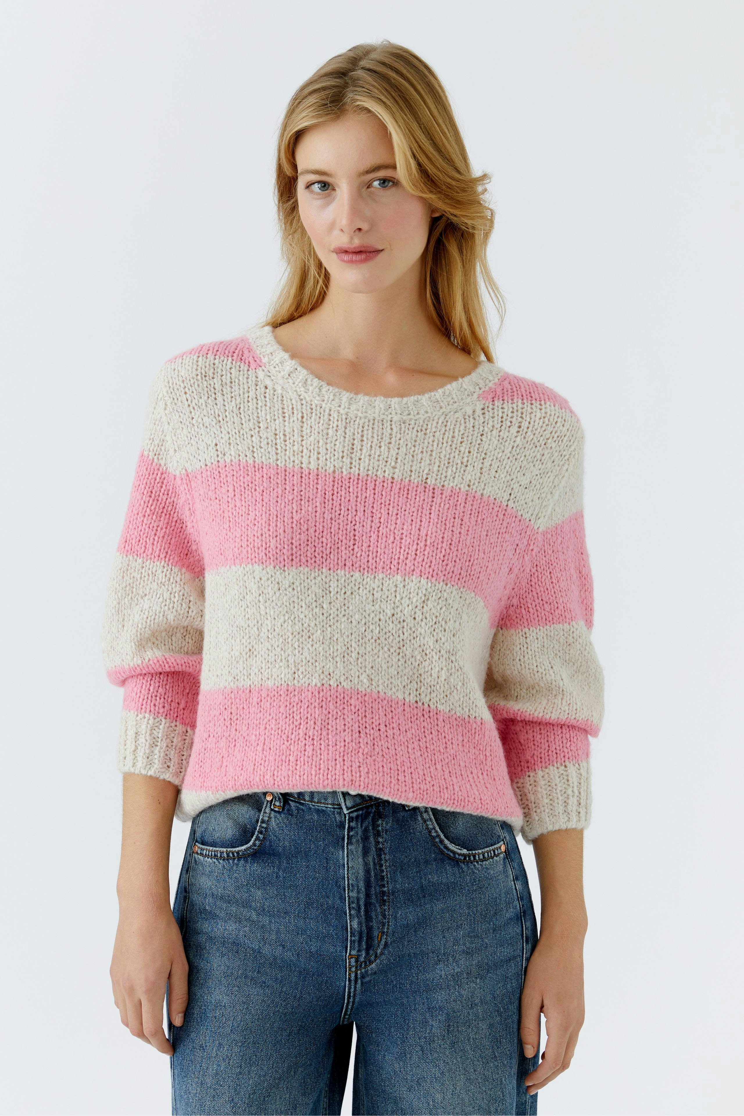 Damen-Pullover in rosa-weißen Streifen, lässig kombiniert mit Jeans, präsentiert von einer Frau.