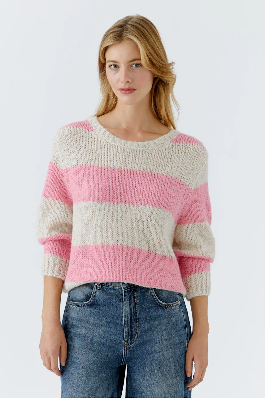 Damen-Pullover in rosa-weißen Streifen, lässig kombiniert mit Jeans, präsentiert von einer Frau.
