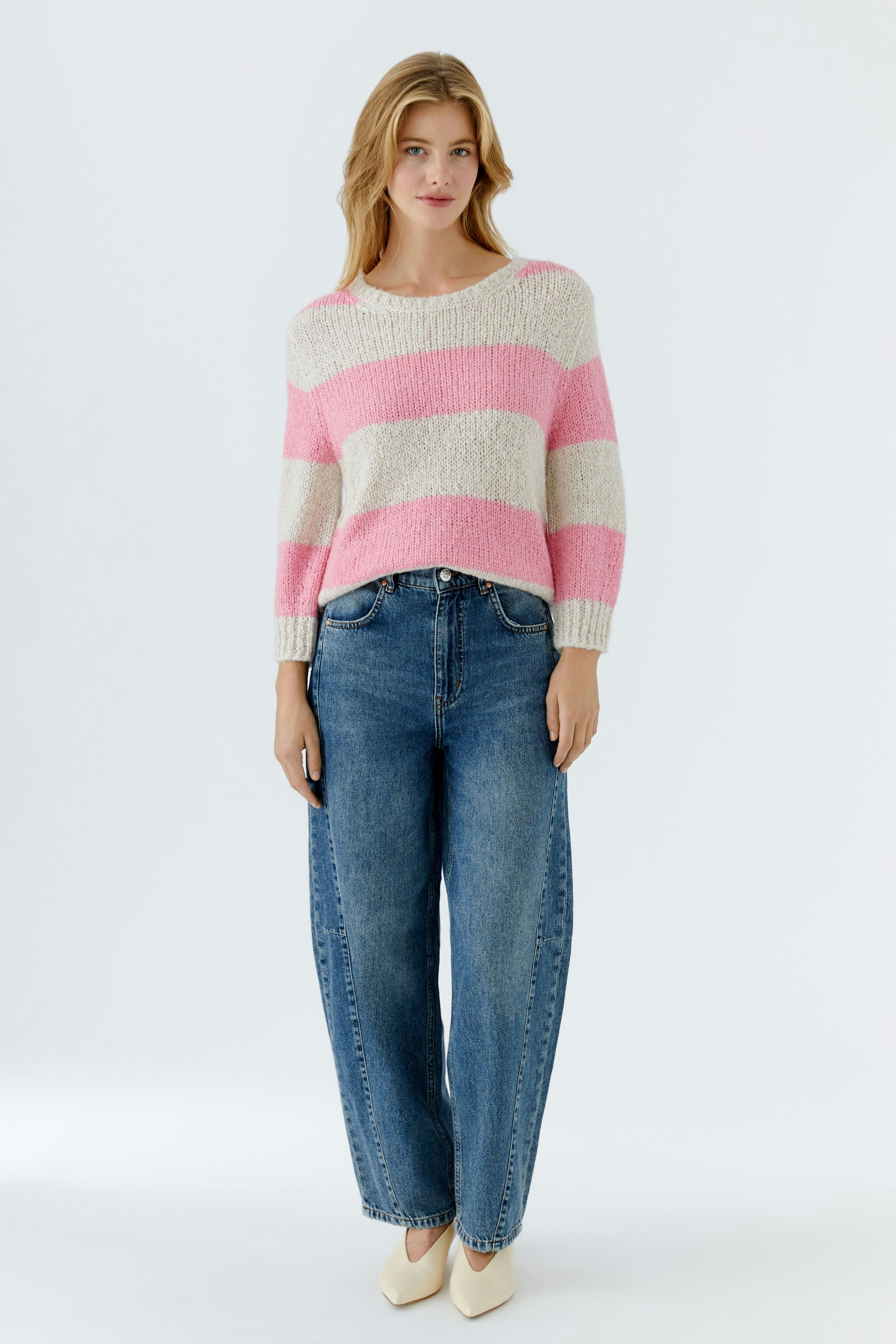Damen-Pullover: Frau in gestreiftem, lässigem Pullover in Rosa und Beige mit lockeren Jeans.