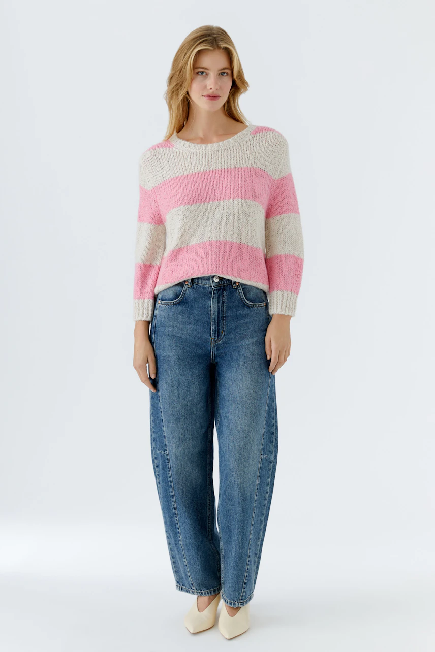 Damen-Pullover: Frau in gestreiftem, lässigem Pullover in Rosa und Beige mit lockeren Jeans.