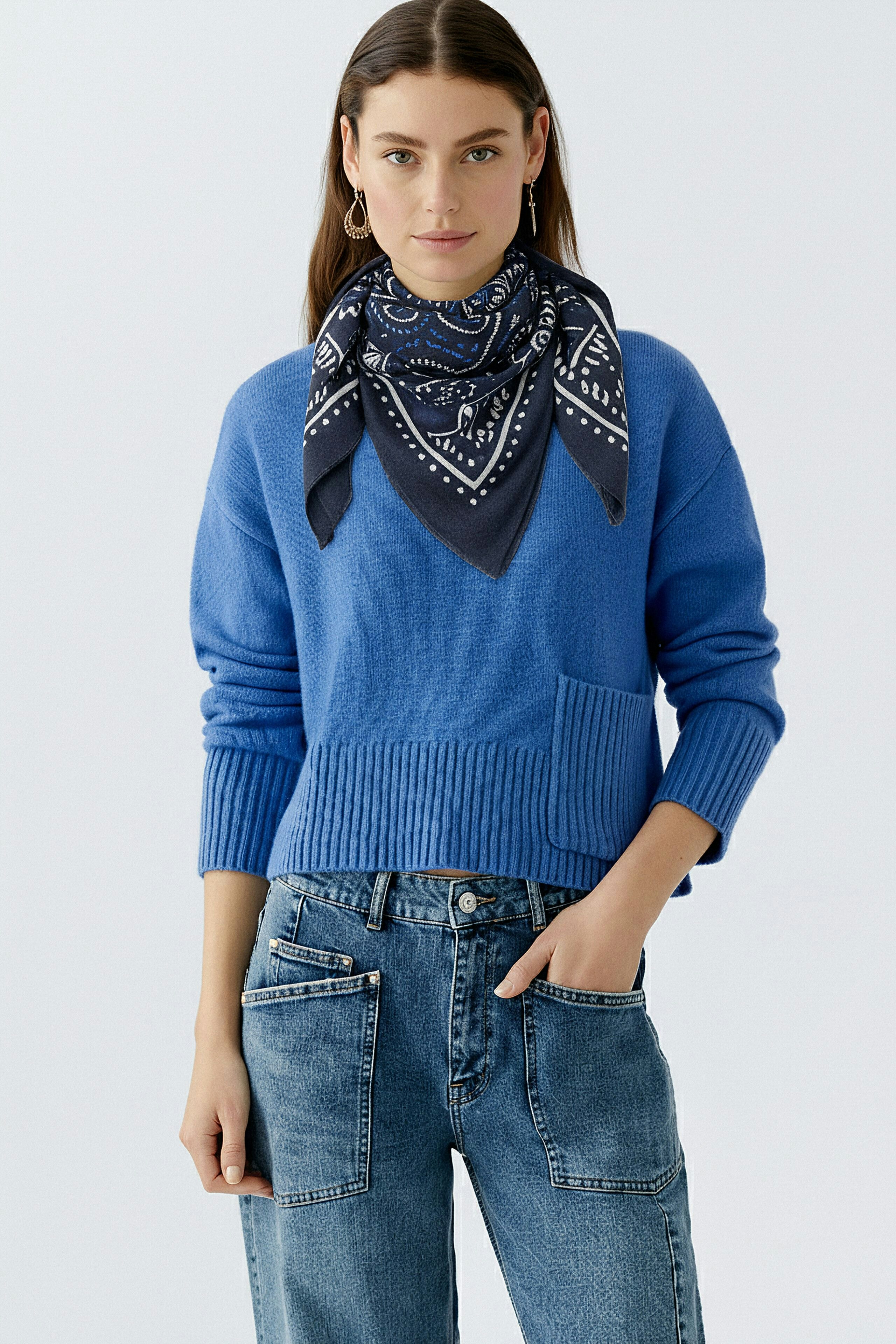Casual scarf: Woman wearing a blue scarf with a stylish pattern, paired with a relaxed outfit.