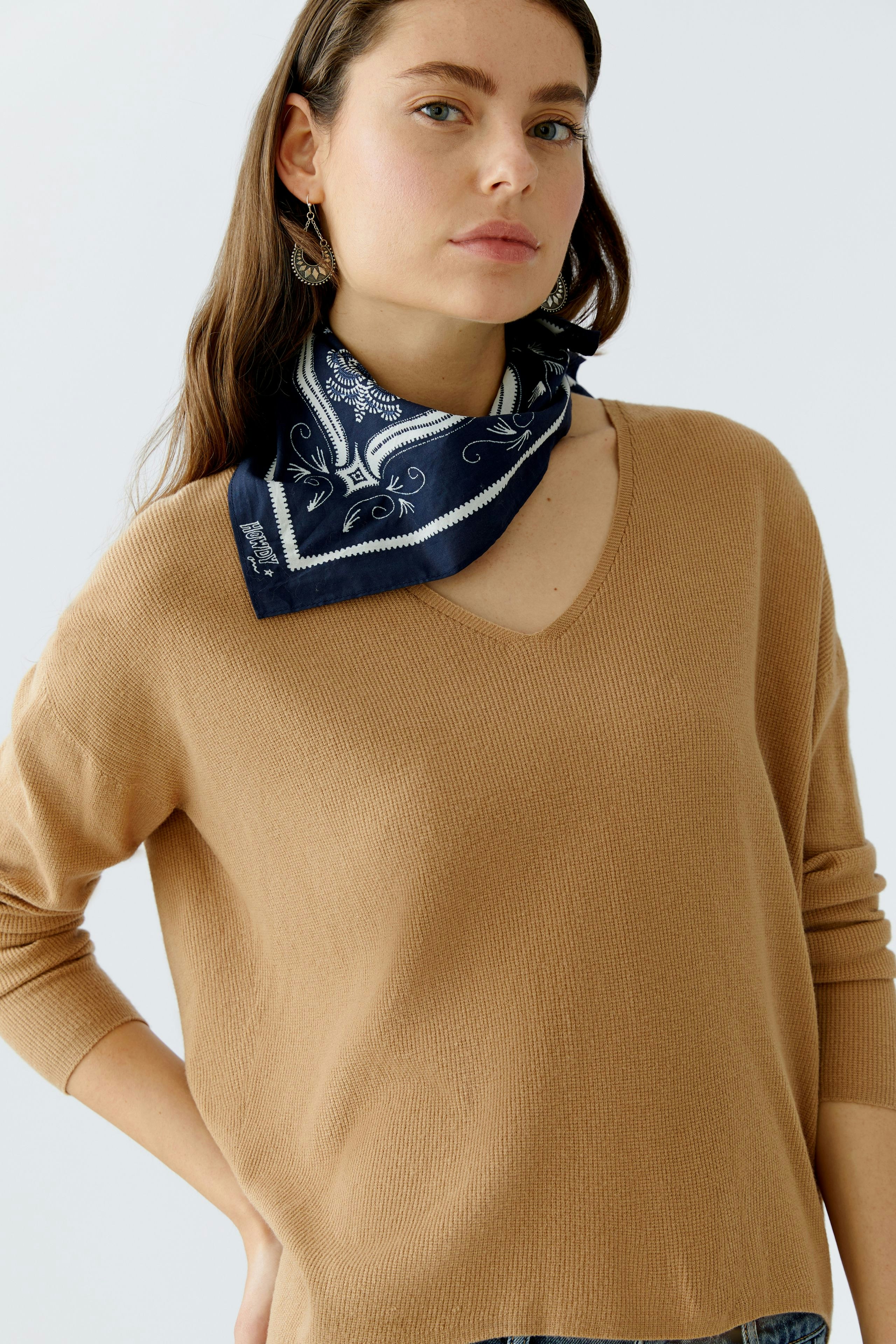 Casual scarf: Woman wearing a navy bandana-style scarf with a stylish pattern around her neck.