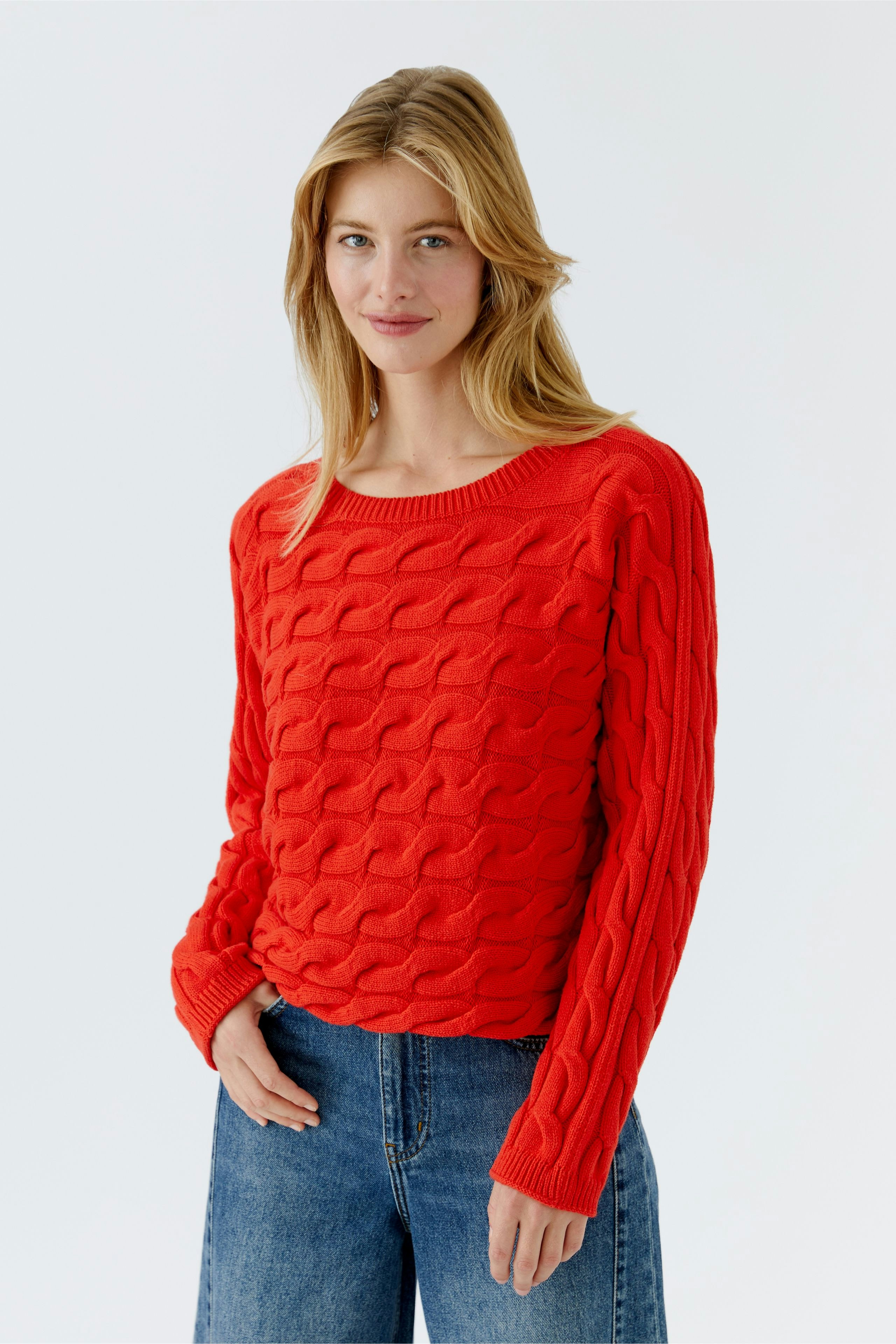 Damen-Pullover: Frau in rotem, strukturiertem Strickpullover mit lässigem Schnitt und Rundhalsausschnitt.