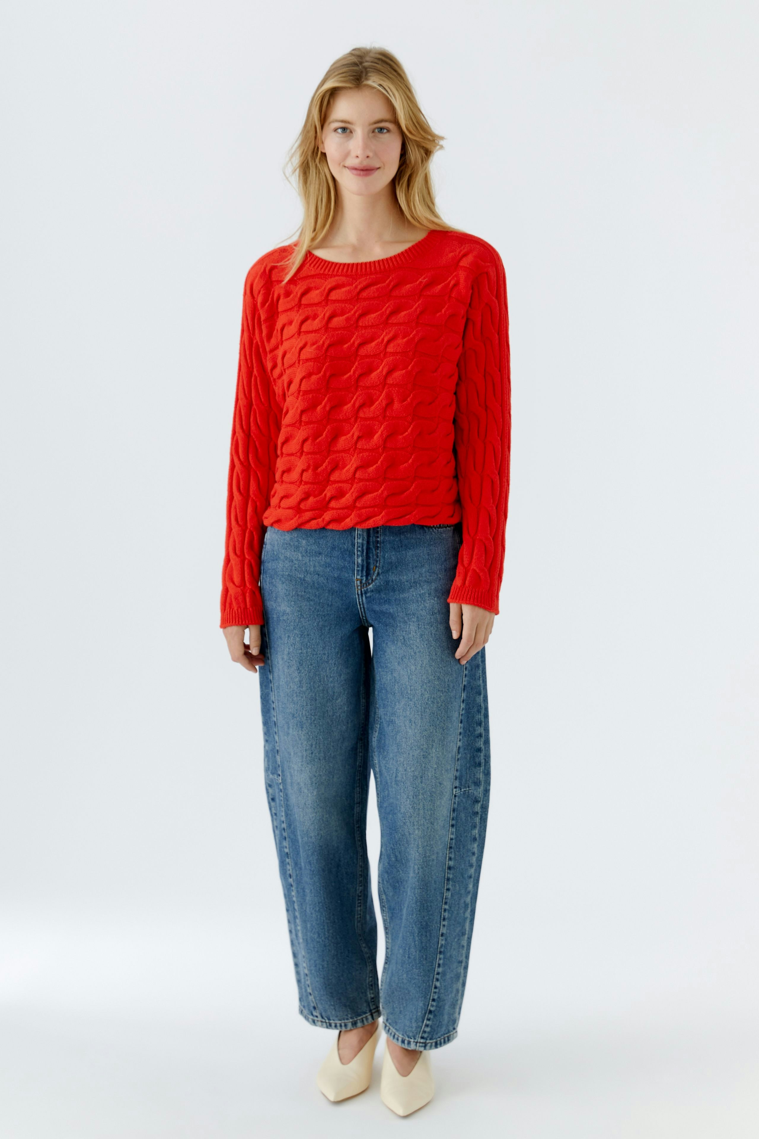 Roter Damen-Pullover mit strukturiertem Muster, lässig kombiniert mit Jeans und Schuhen.