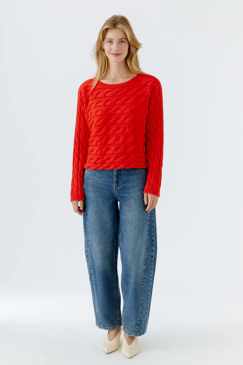 Roter Damen-Pullover mit strukturiertem Muster, lässig kombiniert mit Jeans und Schuhen.