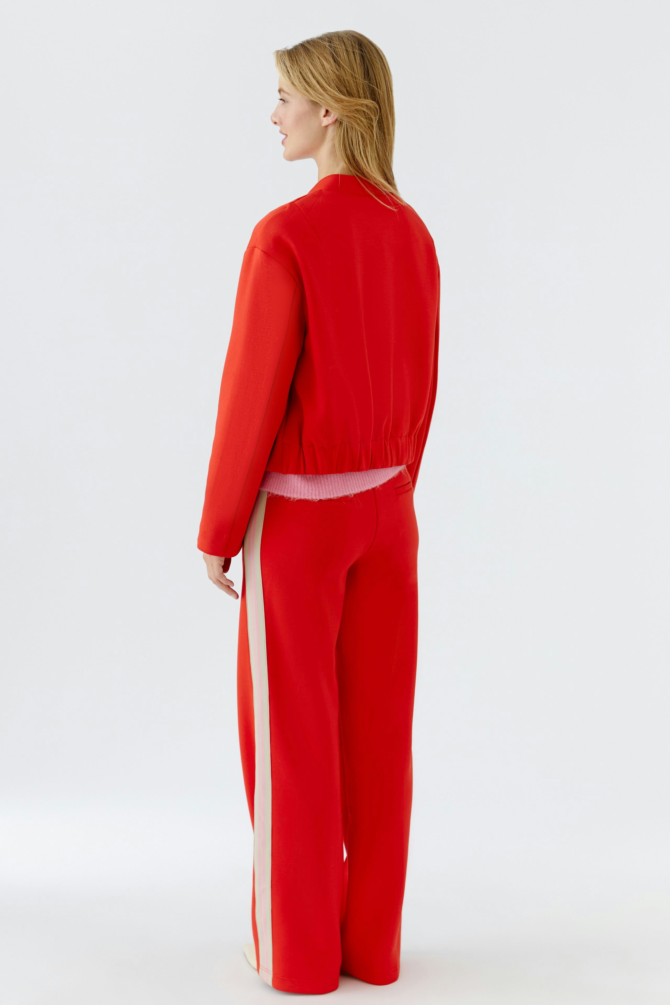 Damen-Blouson: Frau in rotem Blouson mit elastischem Bund und lässiger Passform von hinten.