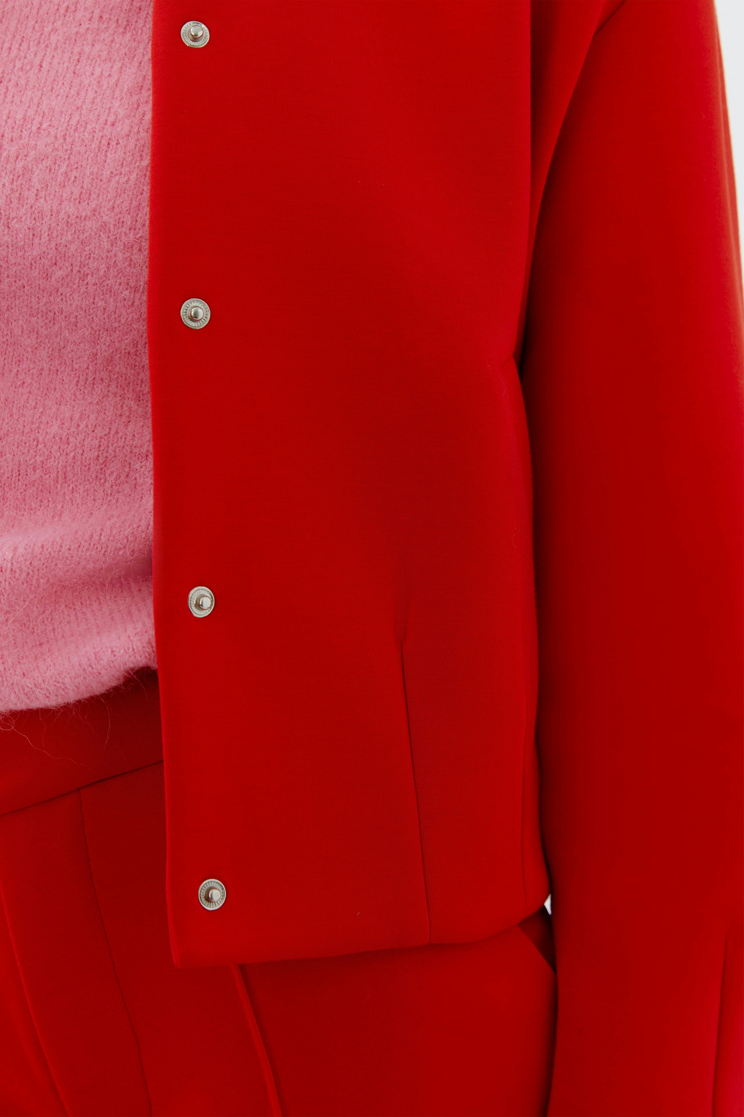 Damen-Blouson: Frau in rotem Blouson mit Druckknöpfen, kombiniert mit einem pinken Pullover.