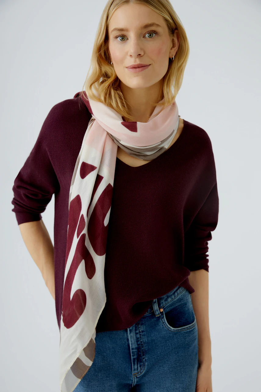 Casual women's pullover: Woman in a burgundy pullover paired with a light scarf, smiling confidently.