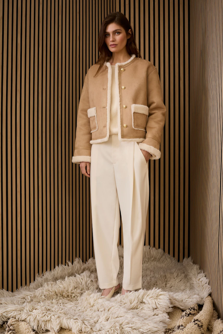 Stylish women's faux leather jacket: A woman in a beige jacket with a cozy lining and relaxed fit.