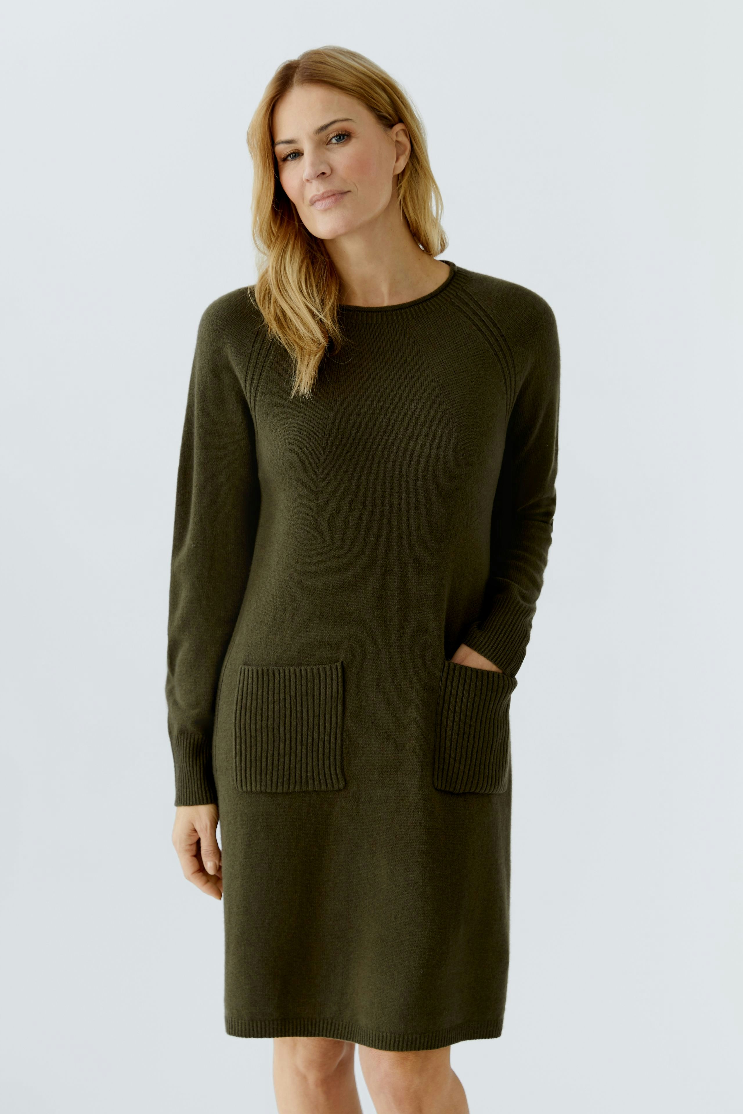 Casual women's knitted dress in olive green with ribbed pockets and long sleeves.