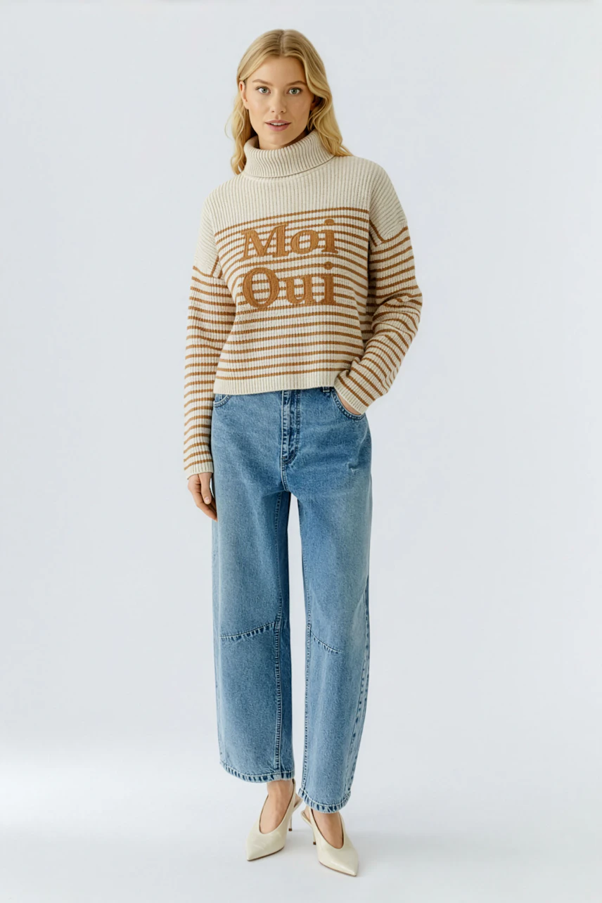 Casual women's pullover: Young woman in a striped pullover with 'Met Oui' lettering and relaxed jeans.