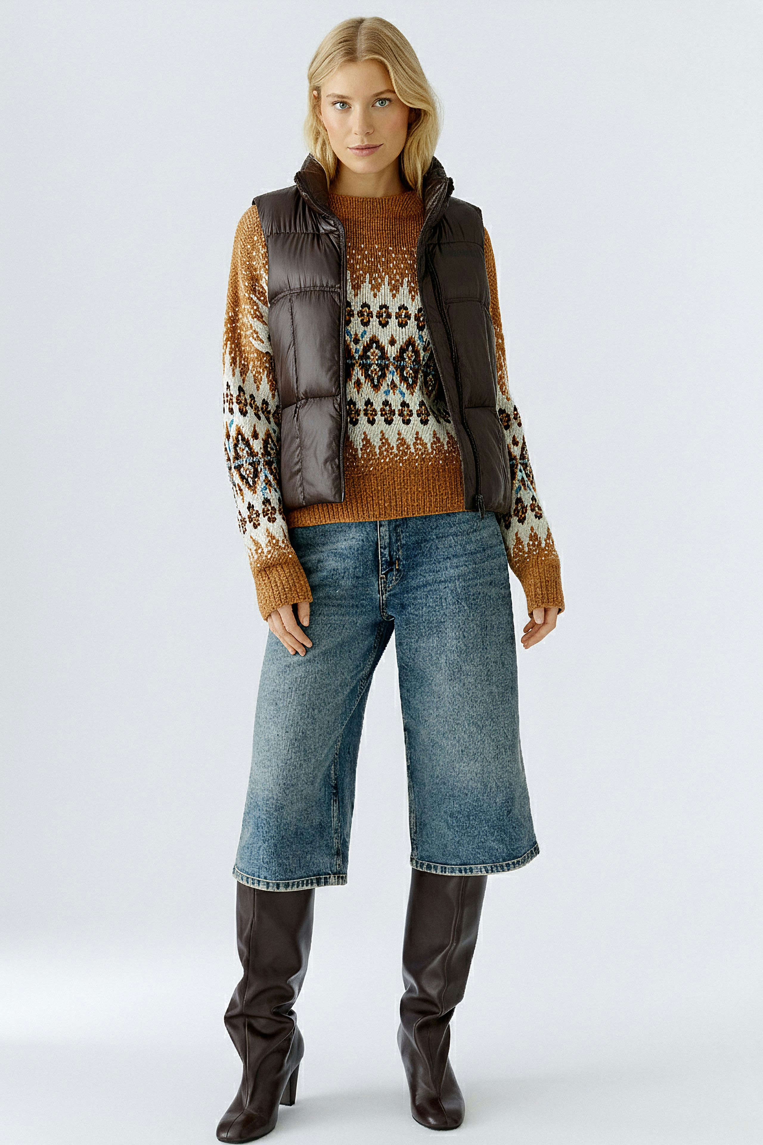 Stylish women's vest: A woman in a brown padded vest over a colorful pullover and wide jeans.