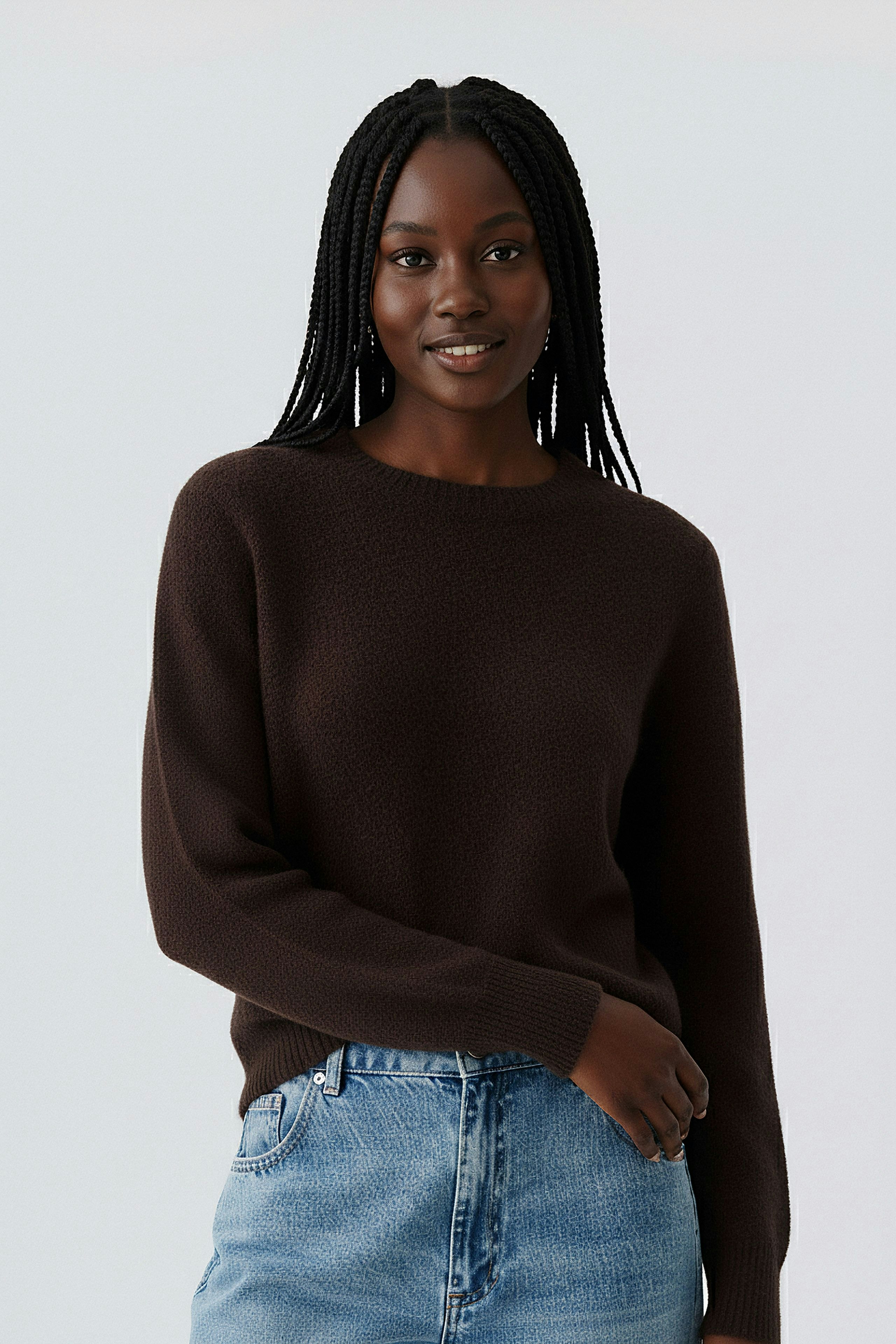 Modern women's pullover: A woman in a brown textured pullover paired with light blue jeans.