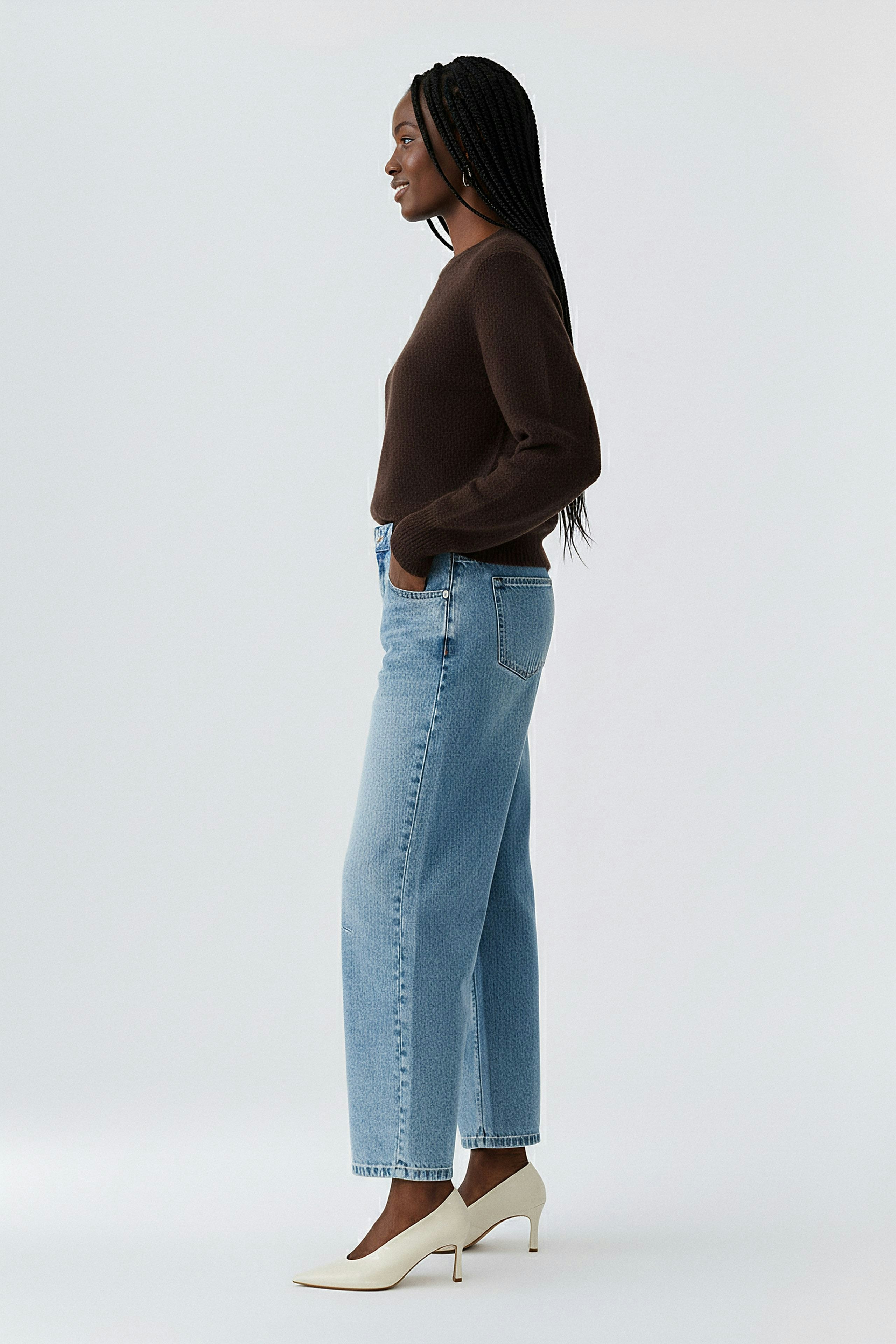 Casual women's pullover: Woman in a brown knit pullover paired with light blue jeans.