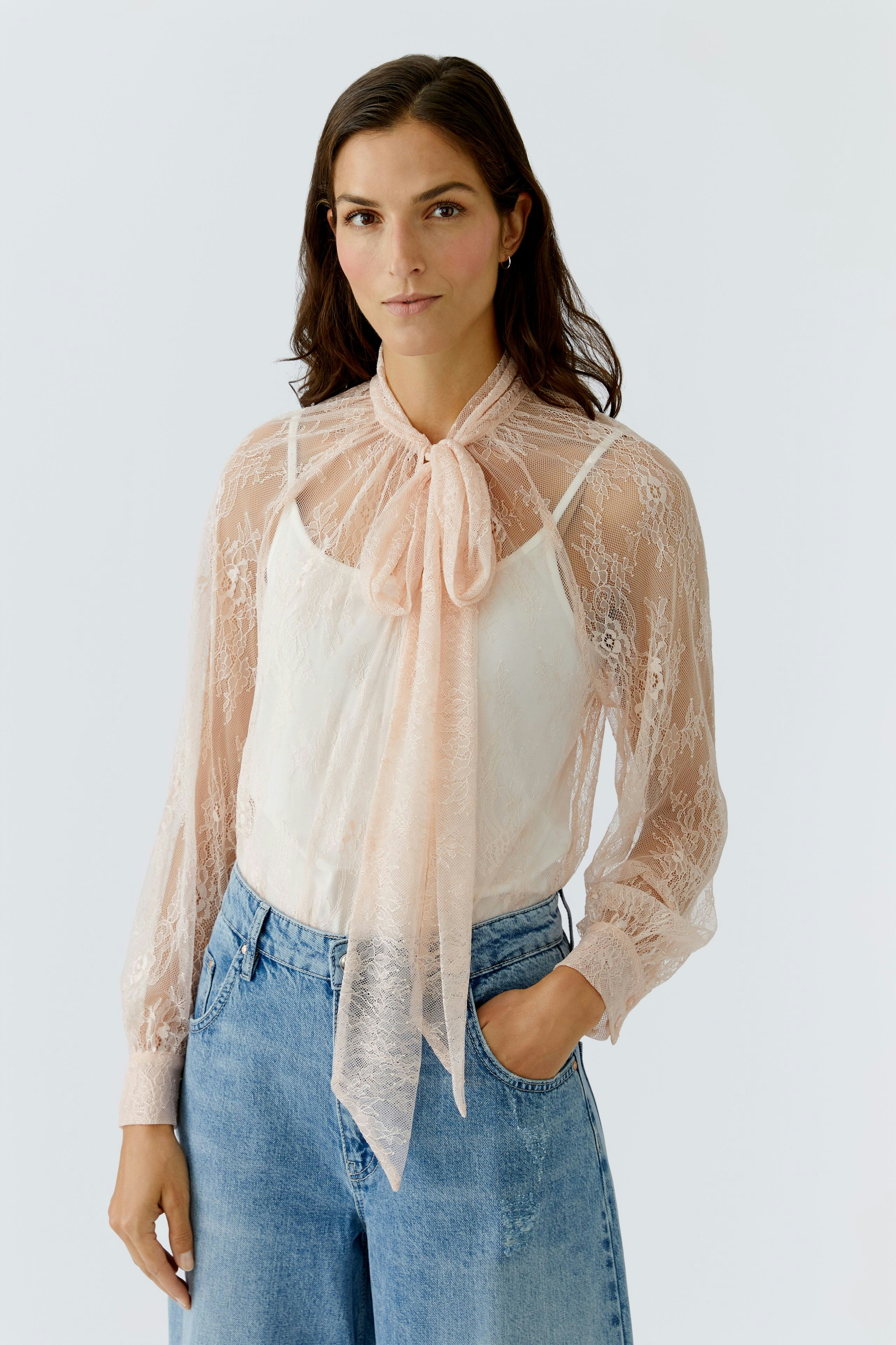 Damen-Bluse: Frau in transparenter Bluse mit Schleife und lässigen Jeans, strahlt Selbstbewusstsein aus.