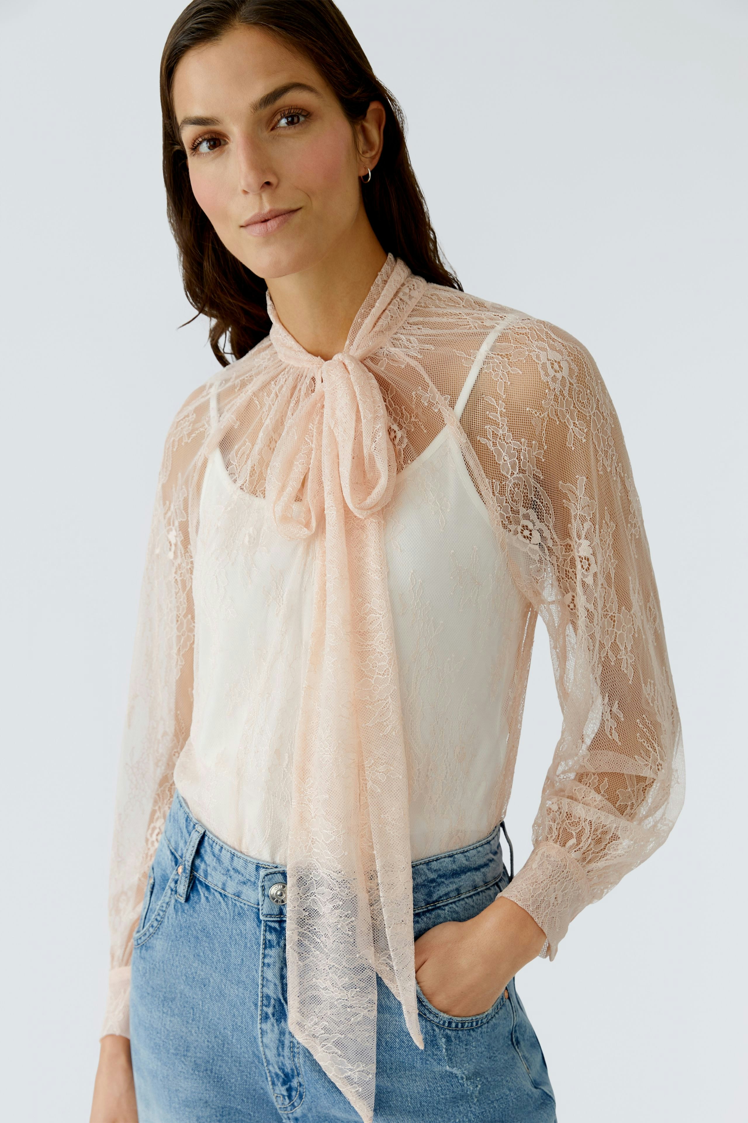 Damen-Bluse: Frau in zarter, transparenter Bluse mit Schleifenkragen und lässigen Jeans.