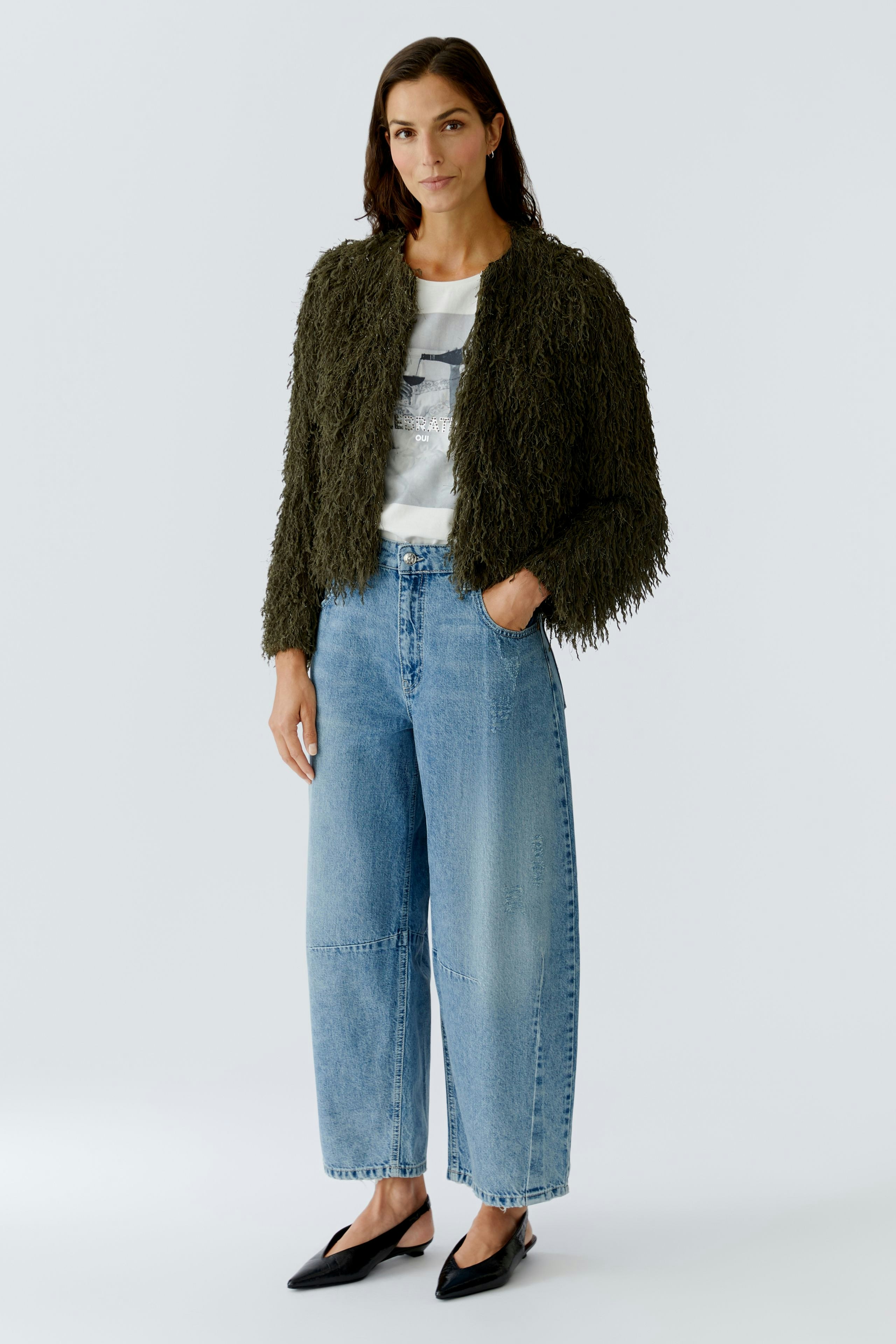 Casual women's jeans: A woman in relaxed-fit barrel jeans paired with a fluffy green jacket.
