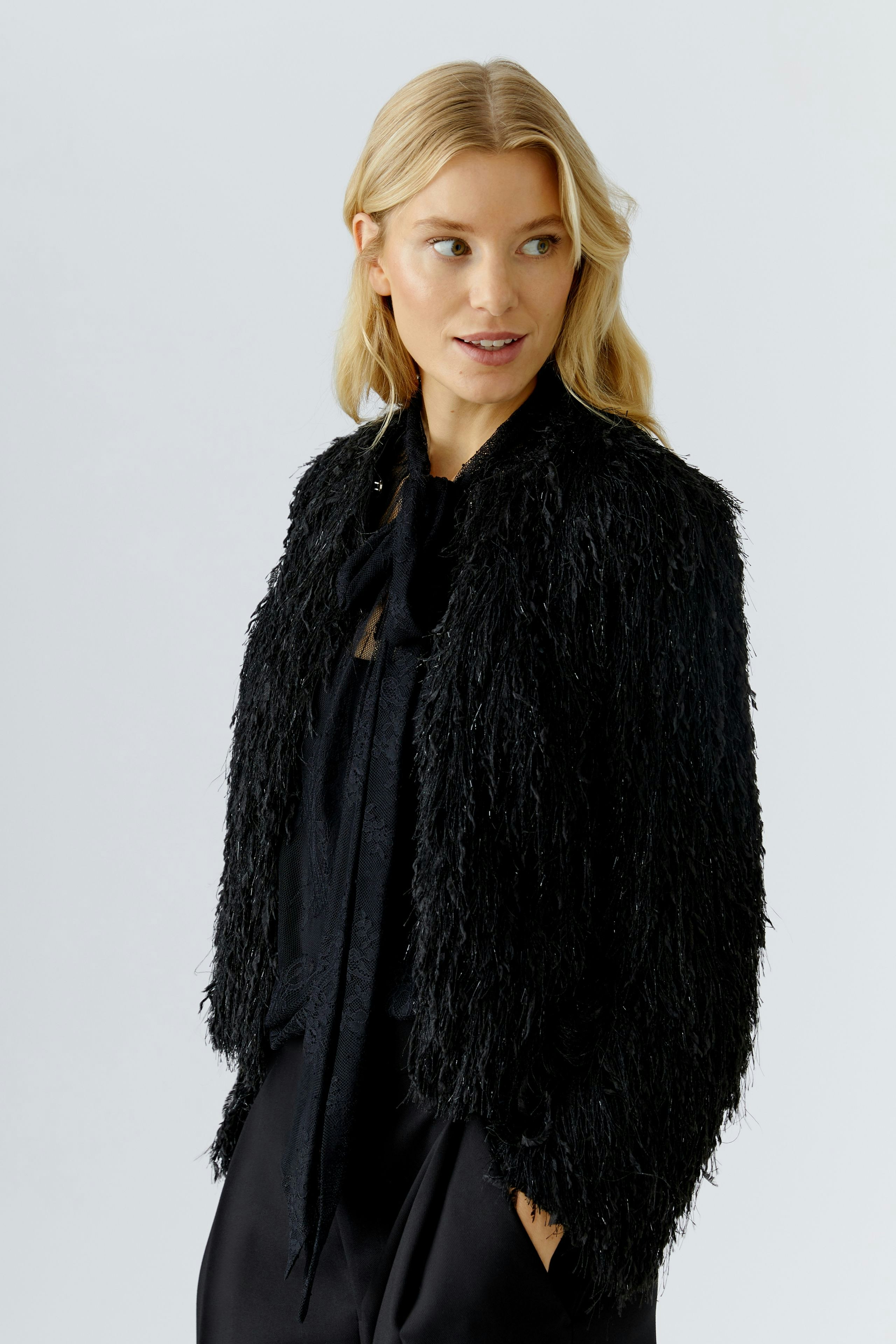 Trendy women's jacket: A woman in a black, textured jacket with a relaxed fit, smiling confidently.