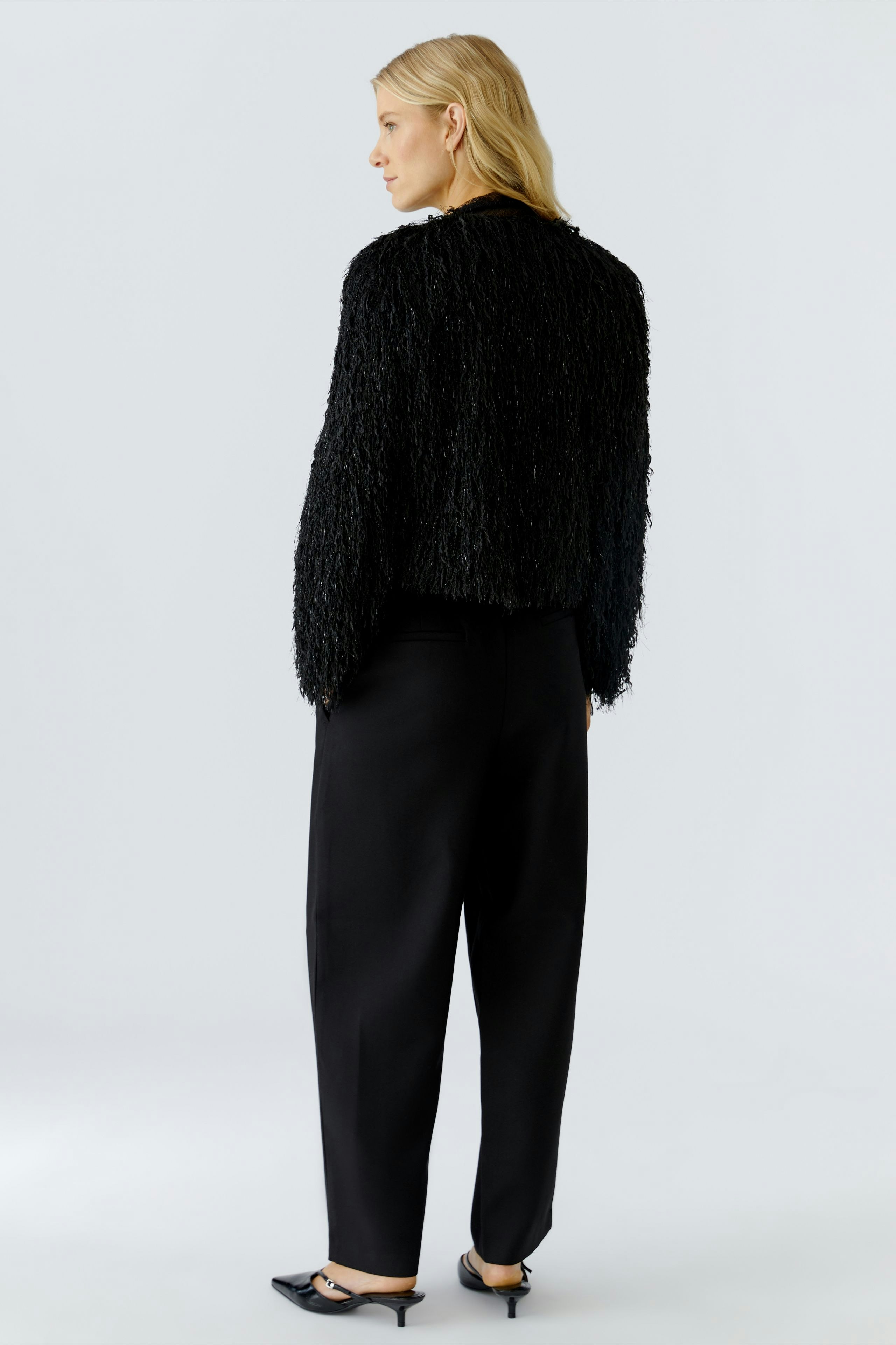 Casual women's jacket: A woman in a textured black jacket paired with loose black trousers.