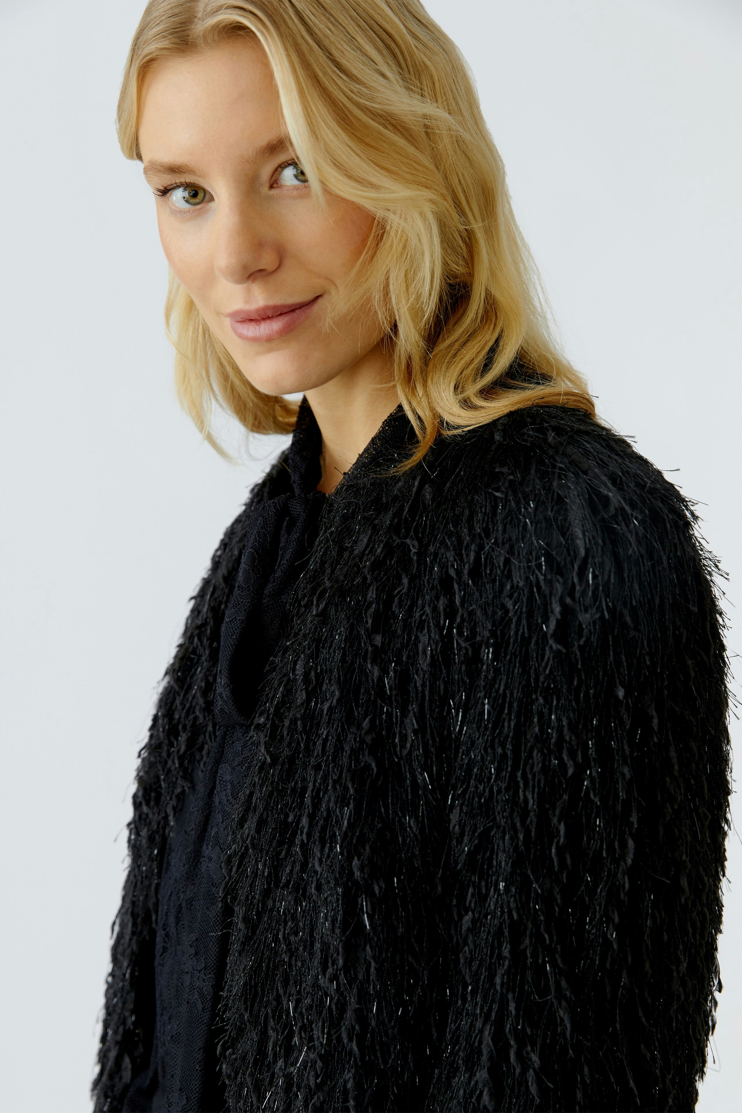 Stylish women's jacket: A woman in a textured black jacket with a relaxed fit, showcasing a modern look.