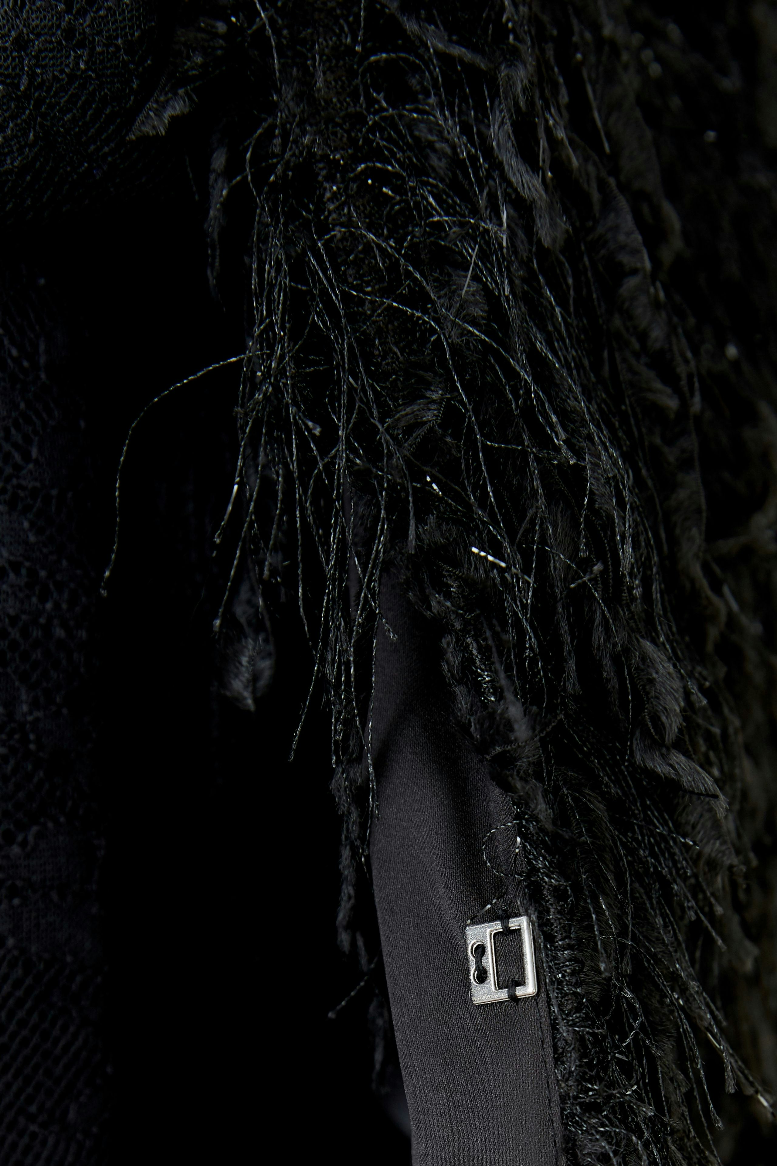 Stylish women's jacket with textured black fabric and unique fringe detailing.