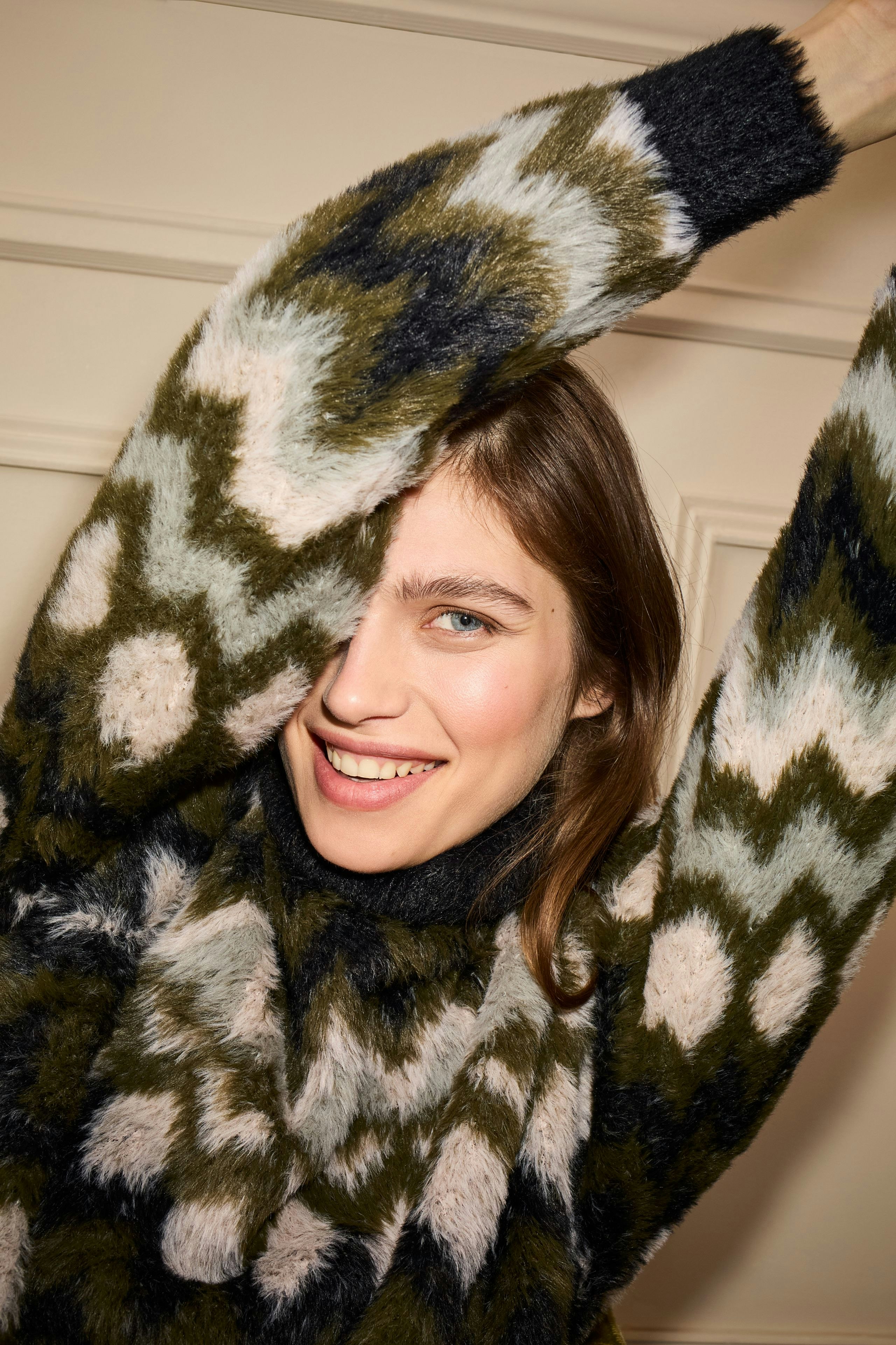 Modern women's pullover: Smiling woman in a cozy patterned pullover with bold colors.