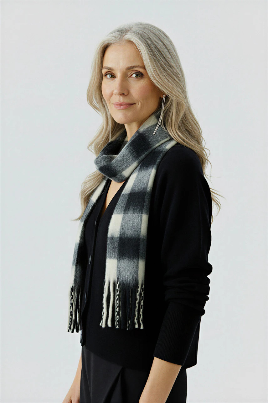 Stylish women's scarf: A woman wearing a black and white checked scarf, paired with a black cardigan.